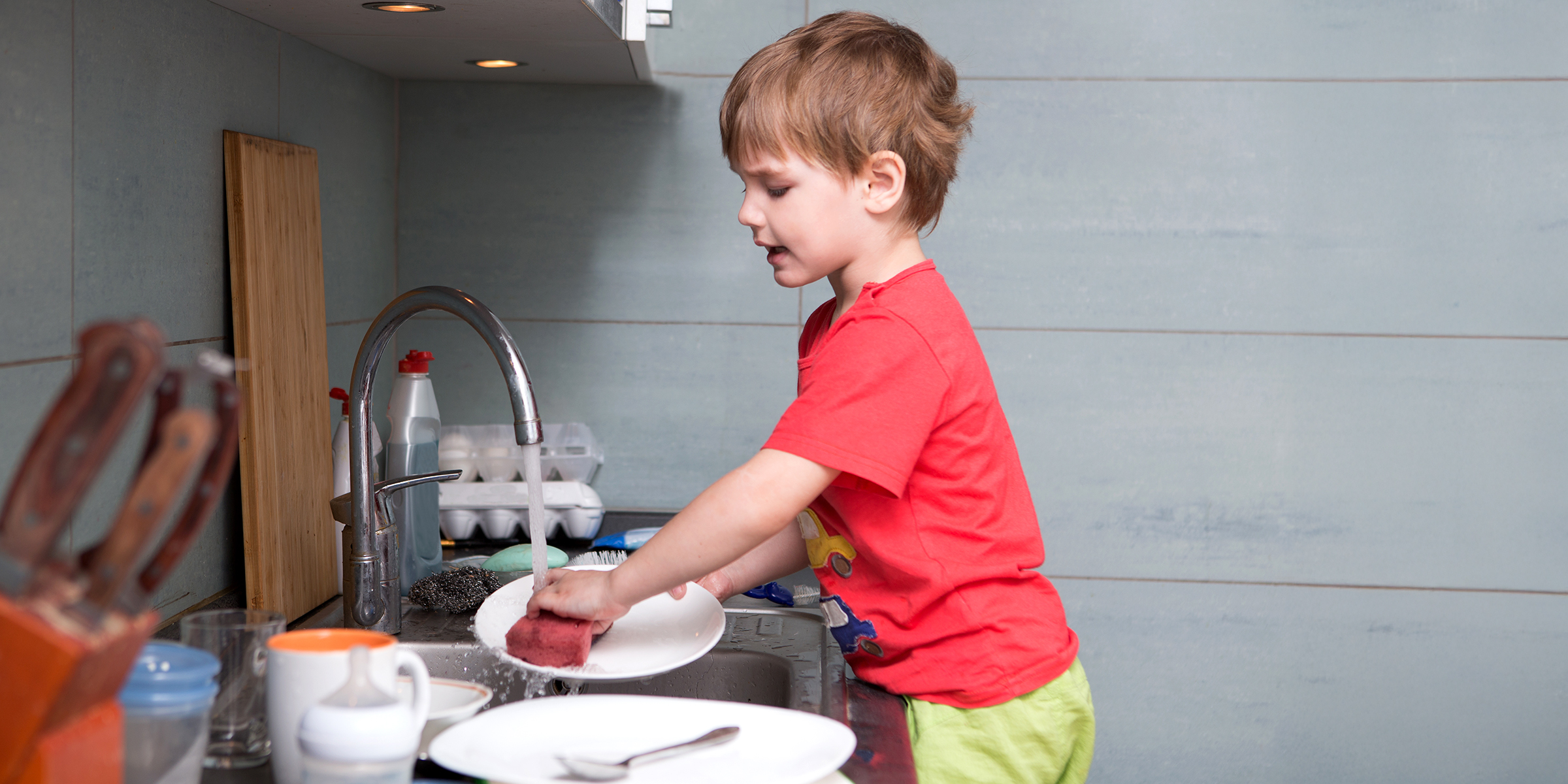 Un niño lavando platos | Fuente: Shutterstock