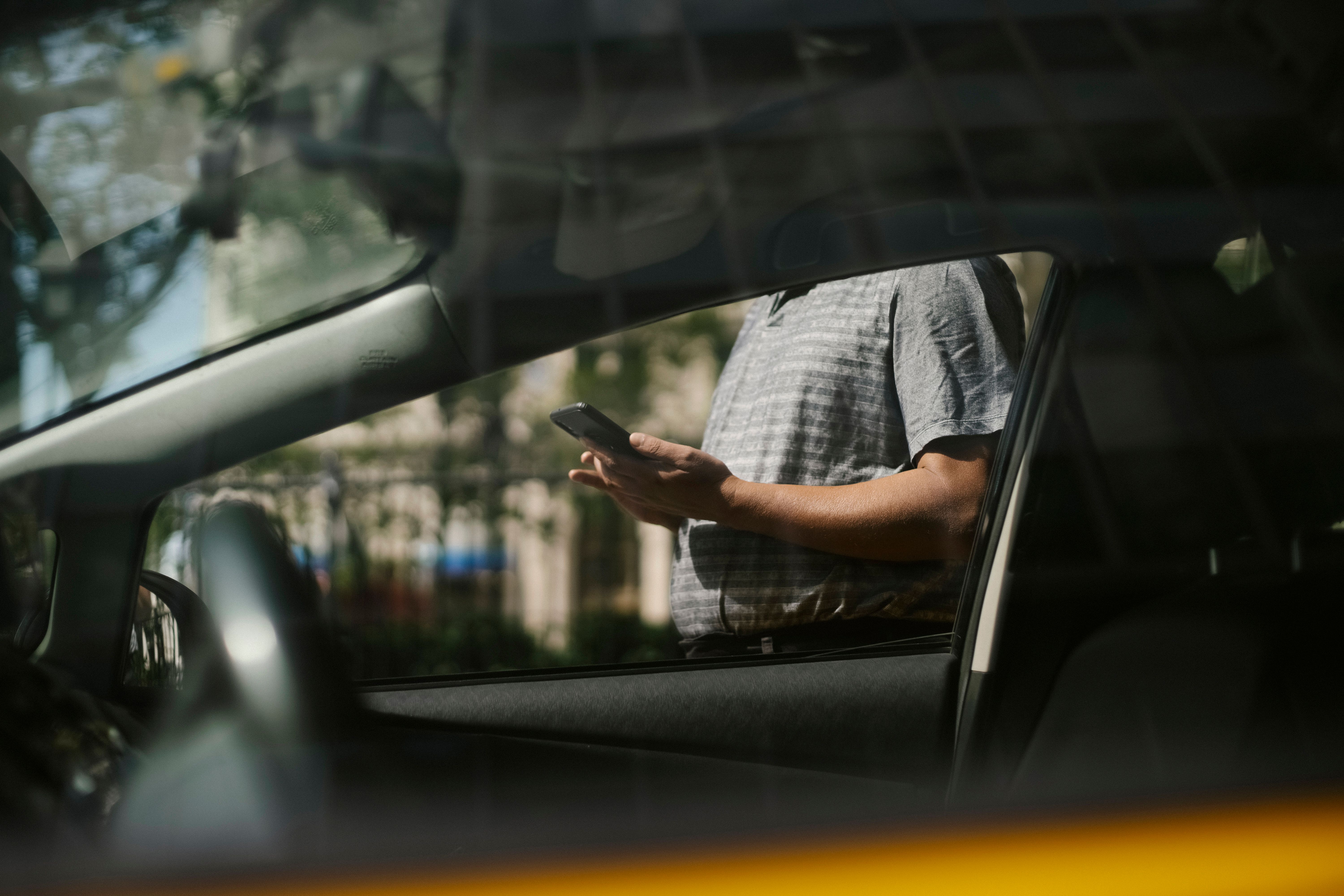 Un uomo in piedi accanto a un'auto mentre usa lo smartphone | Fonte: Pexels