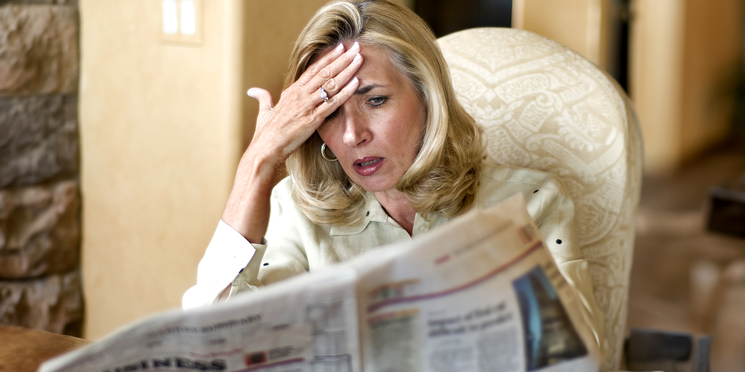 Mujer conmocionada leyendo un periódico | Fuente: Shutterstock