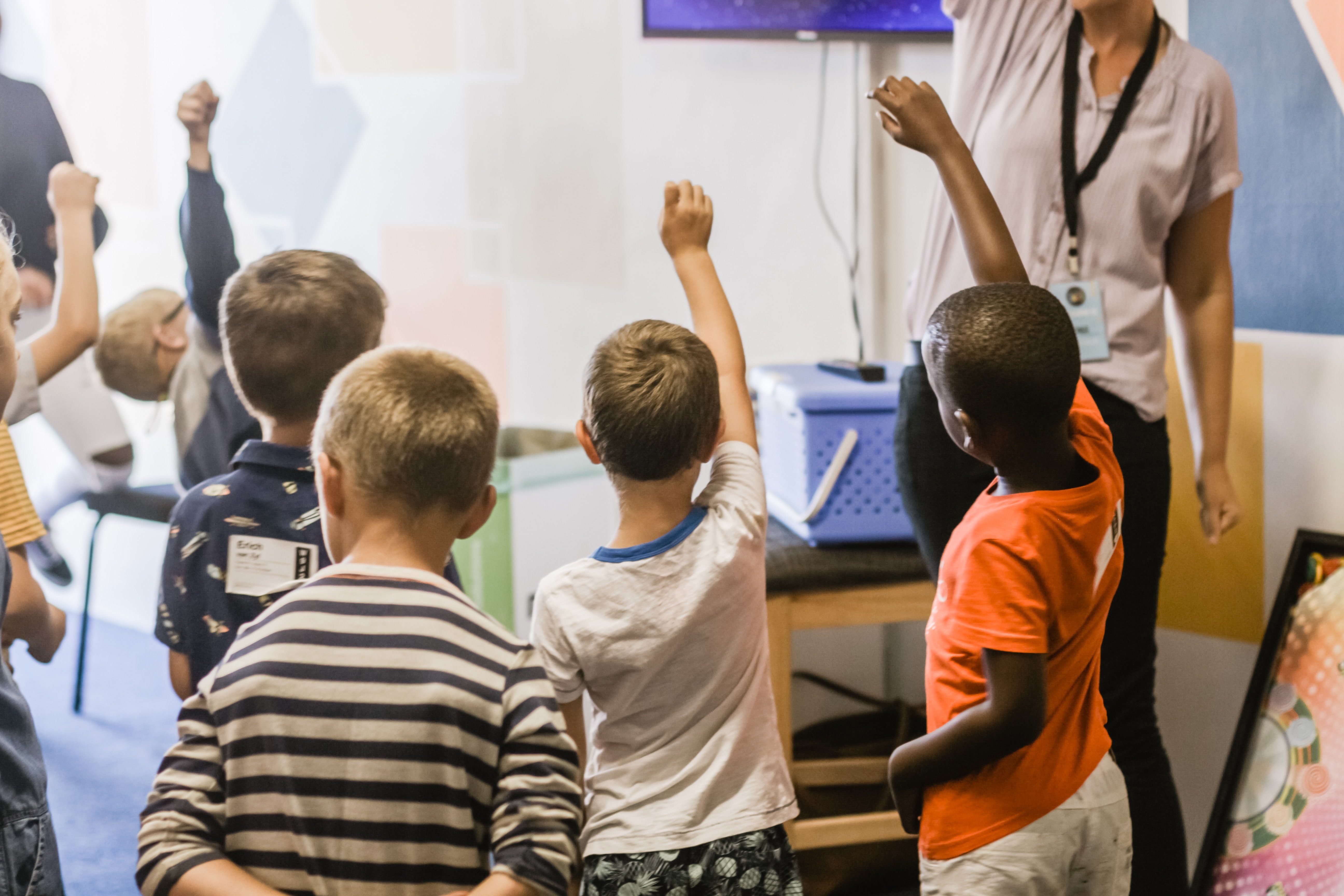 Niños pequeños levantando sus manos en clase. | Imagen: Ben Mullins / Unsplash