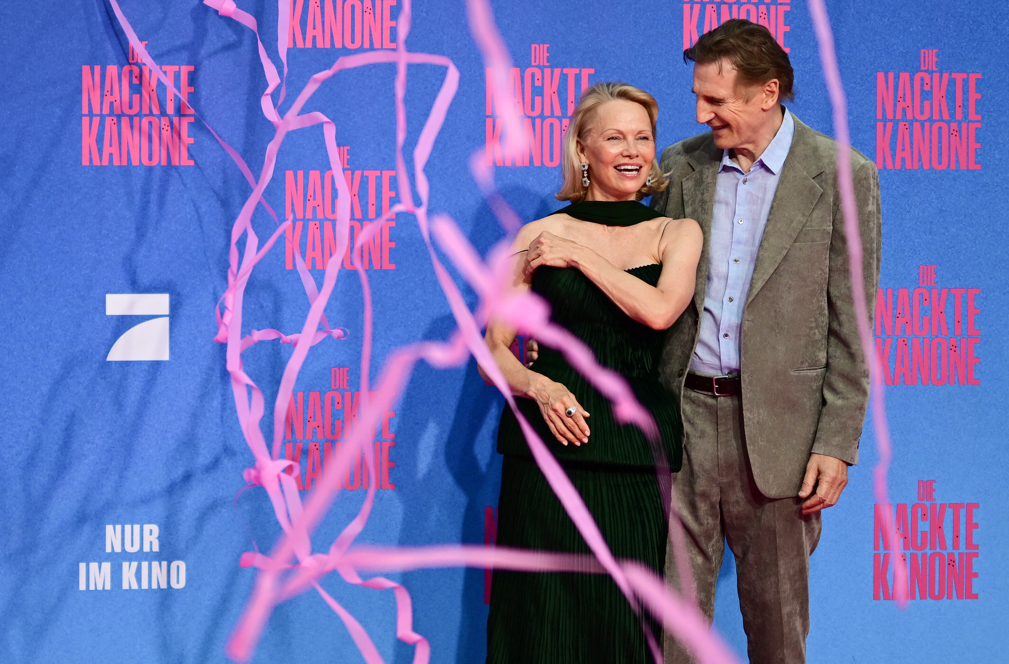 Liam Neeson y Pamela Anderson posan en la alfombra roja a su llegada al estreno en Alemania de “The Naked Gun” en Berlín, el 24 de julio de 2025. | Fuente: Getty Images
