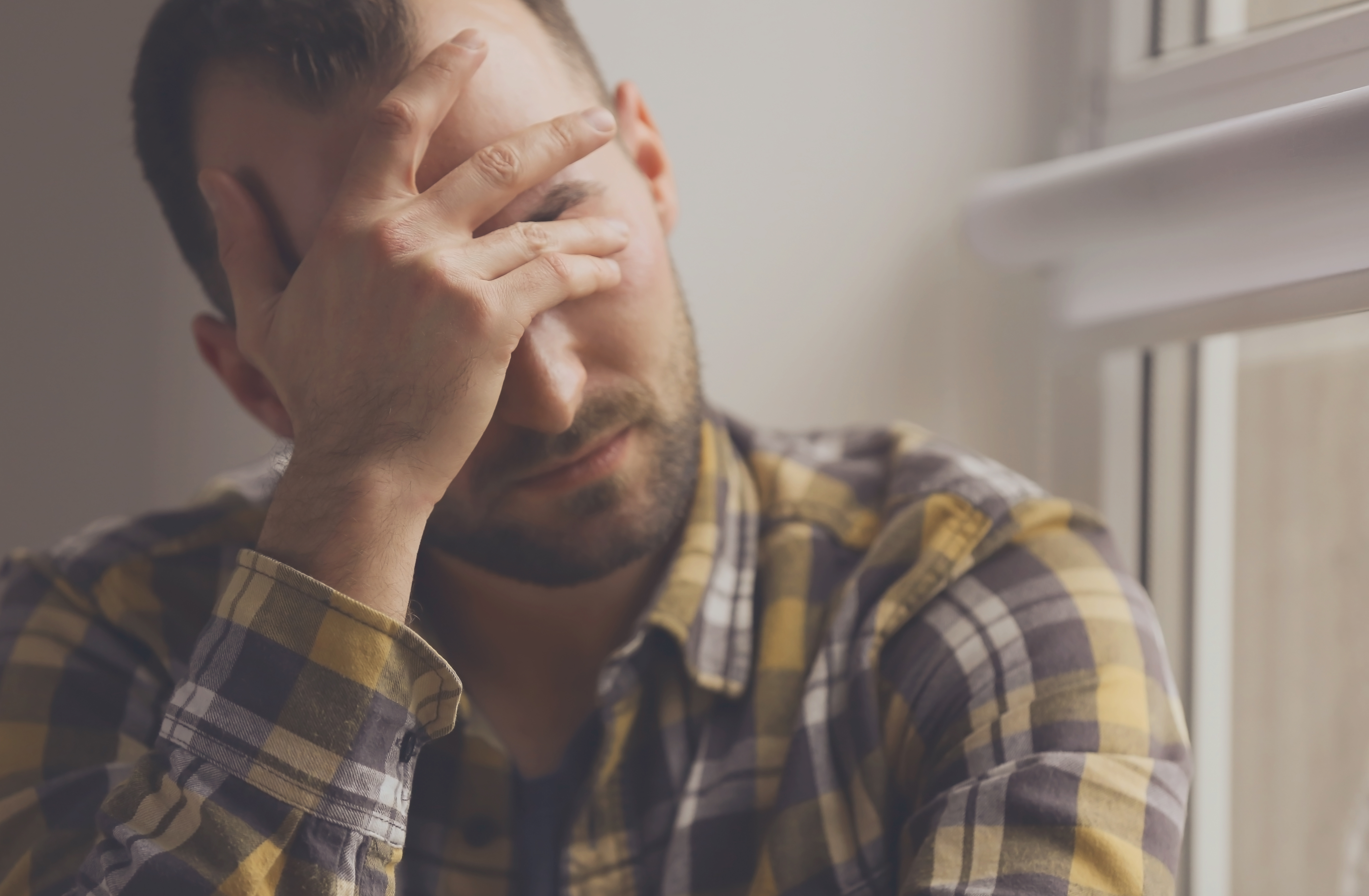 Hombre deprimido cerca de una ventana. | Fuente: Shutterstock