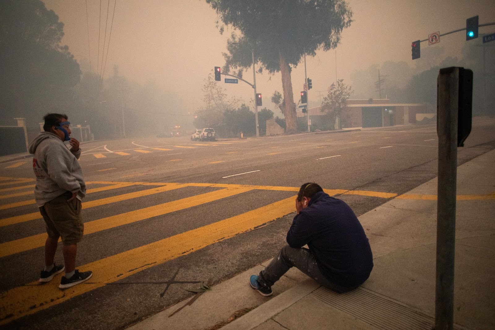 Personas que se detienen a tomar aliento mientras evacuan a lo largo de Sunset Boulevard durante el incendio de Palisades el 7 de enero de 2025. | Fuente: Getty Images