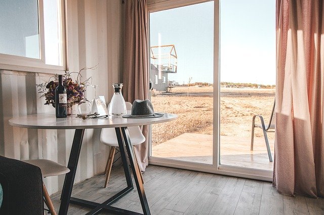 Una habitación con puerta corrediza transparente y mesa con objetos encima. | Foto: Pixabay