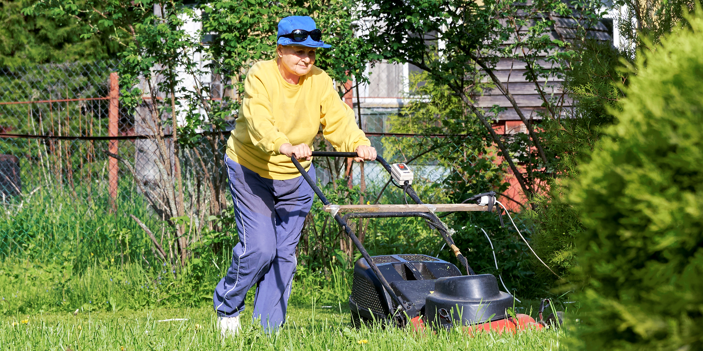 Una mujer cortando el césped | Fuente: Shutterstock