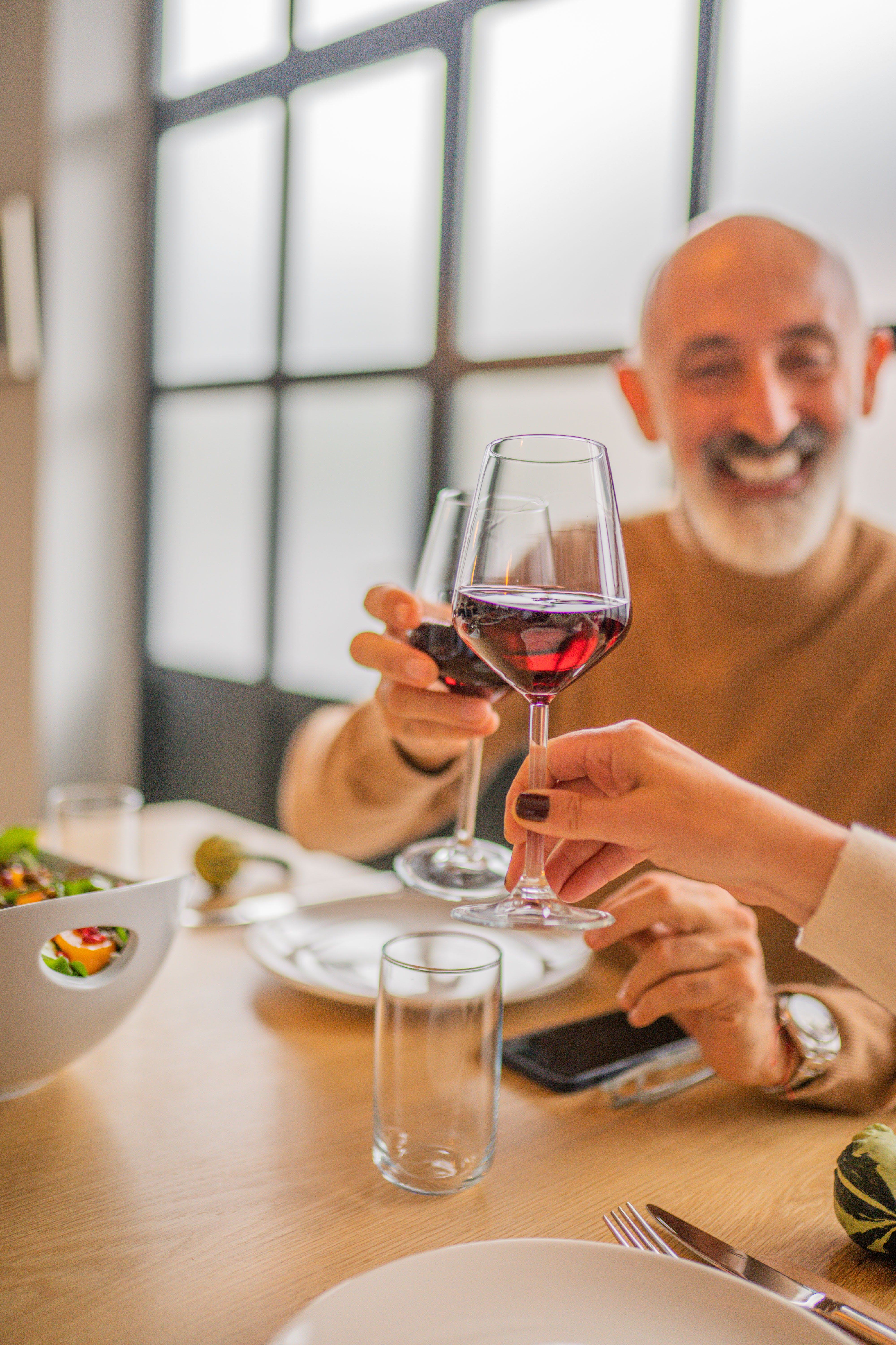 Hombre feliz brindando mientras sostiene una copa de vino tinto | Fuente: Pexels