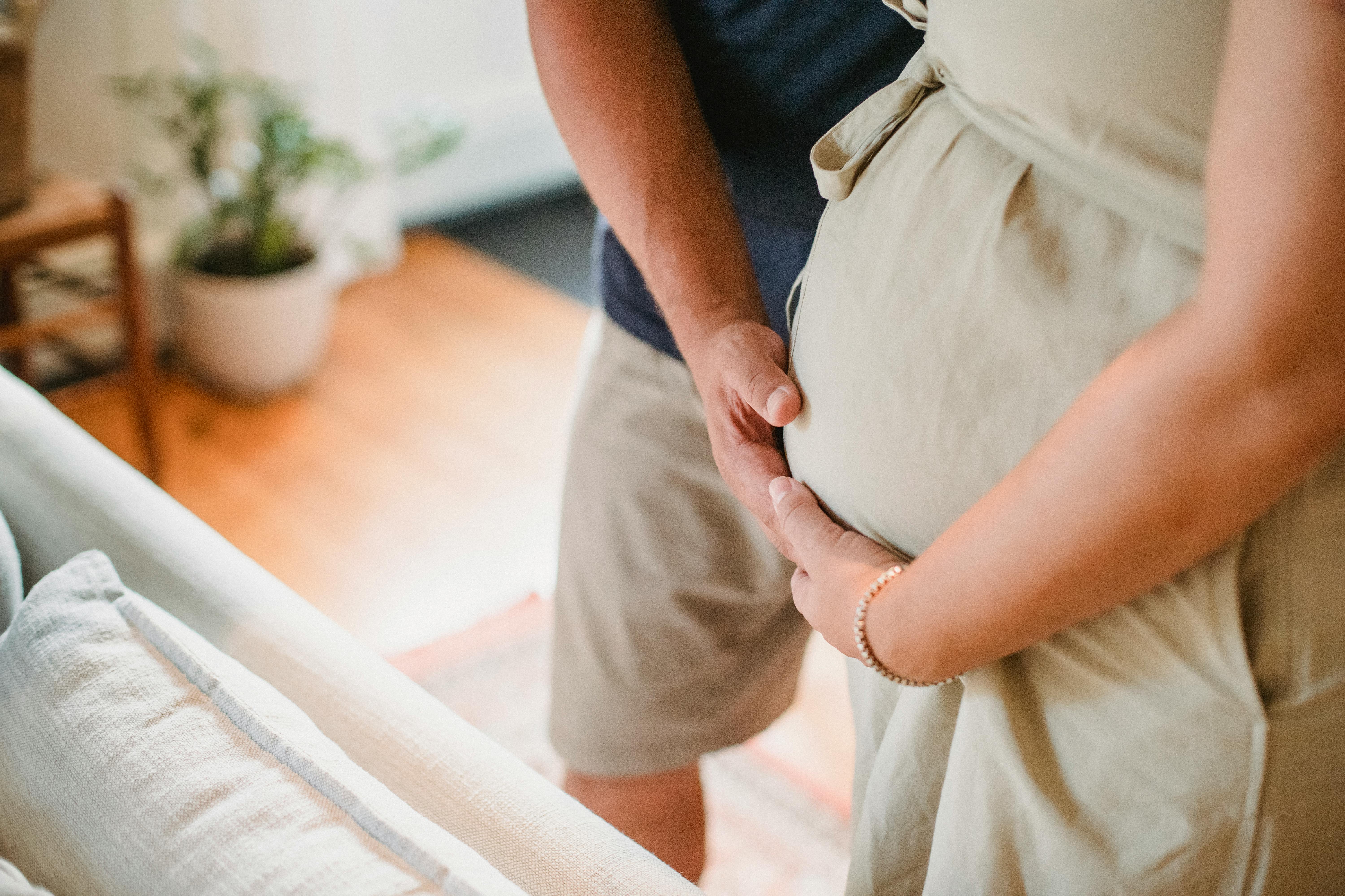 Un hombre y una mujer acariciando un vientre de embarazada | Fuente: Pexels