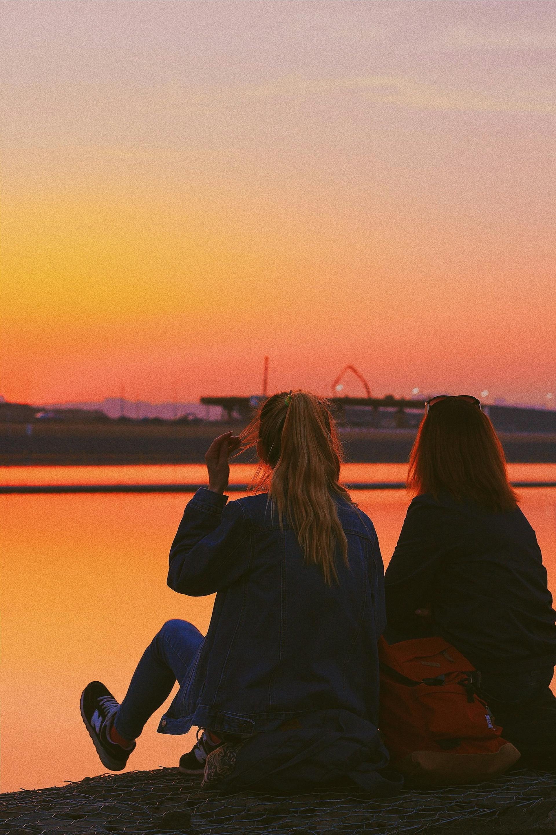 Dos adolescentes sentadas junto a un lago | Foto: Pexels