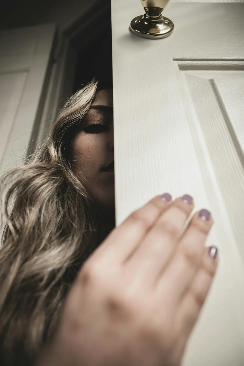 Una mujer espiando detrás de una puerta | Fuente: Pexels