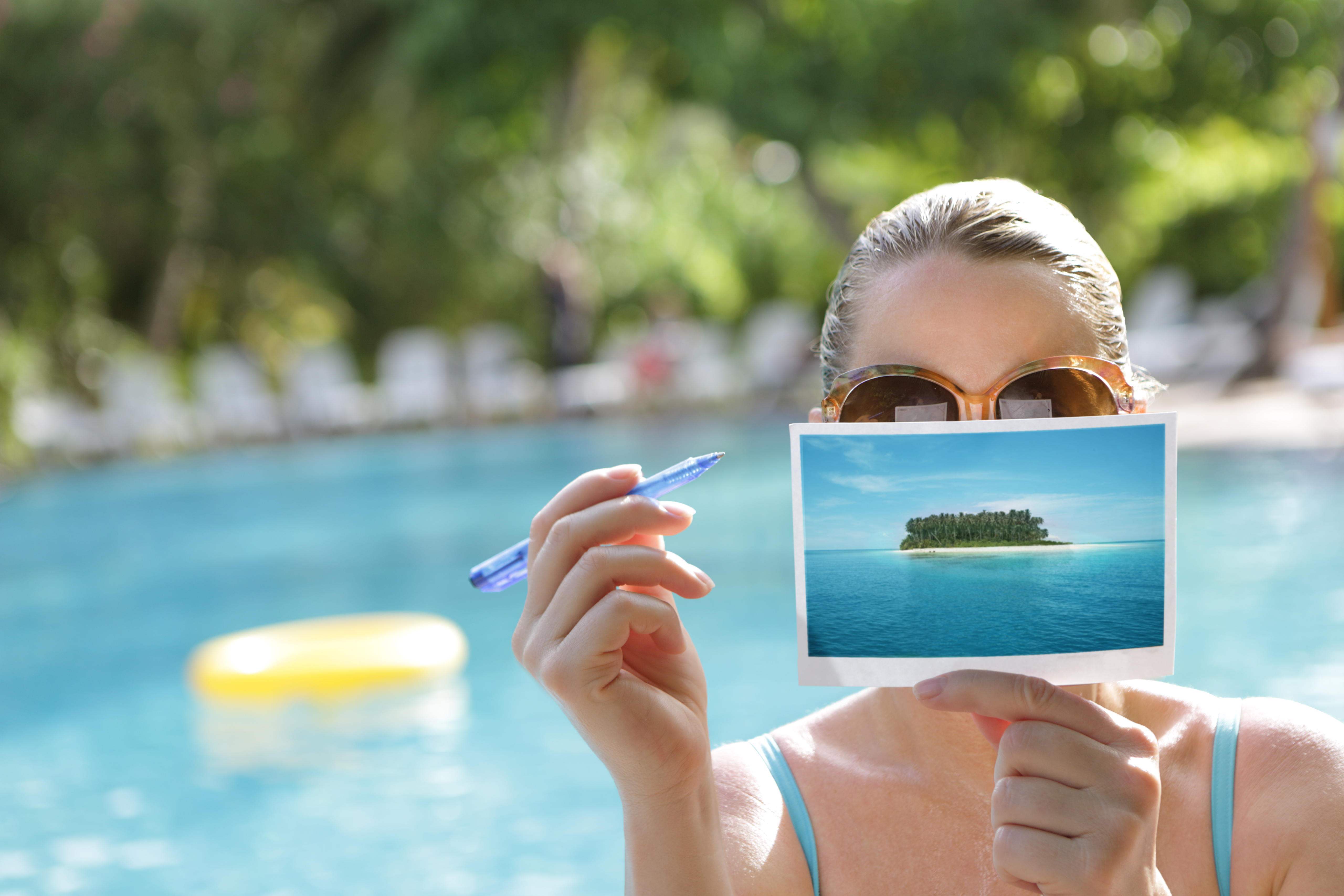 Mujer escribiendo una postal junto a la piscina | Fuente: Getty Images