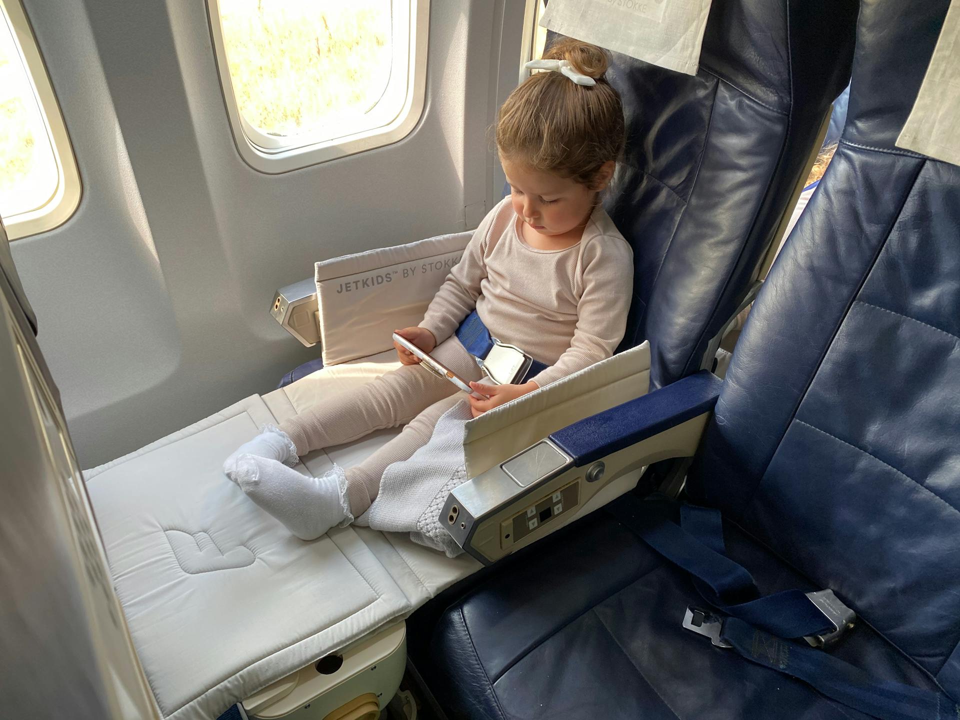 Niña sujetando una tableta en un avión | Fuente: Pexels