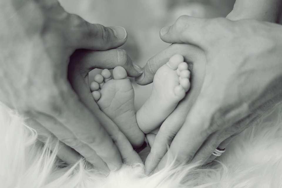 Papá y mamá tomando los pies de su bebé entre sus manos. | Imagen: Pixabay