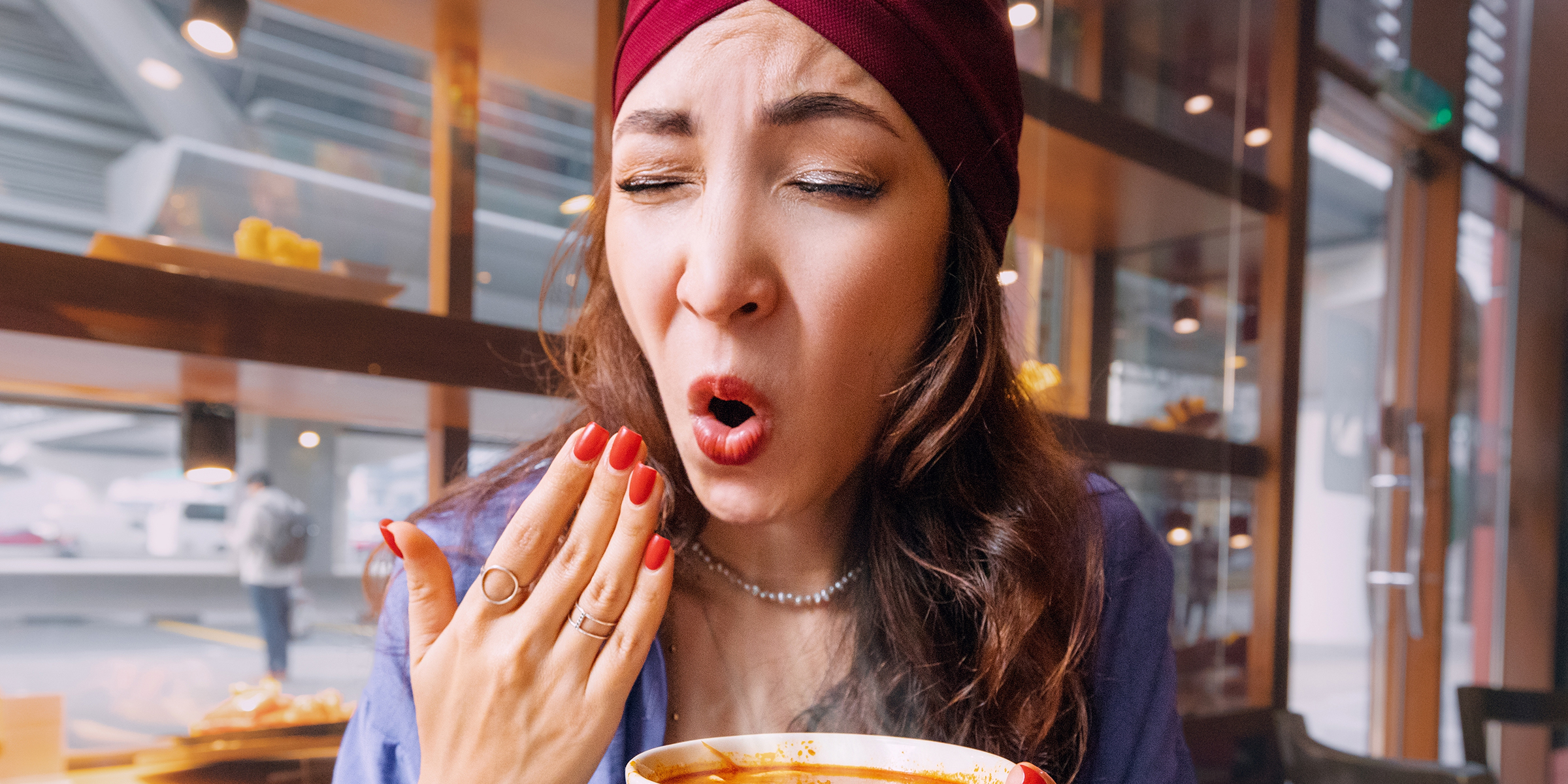 Una mujer haciendo muecas y abanicándose con la boca abierta | Fuente: Shutterstock