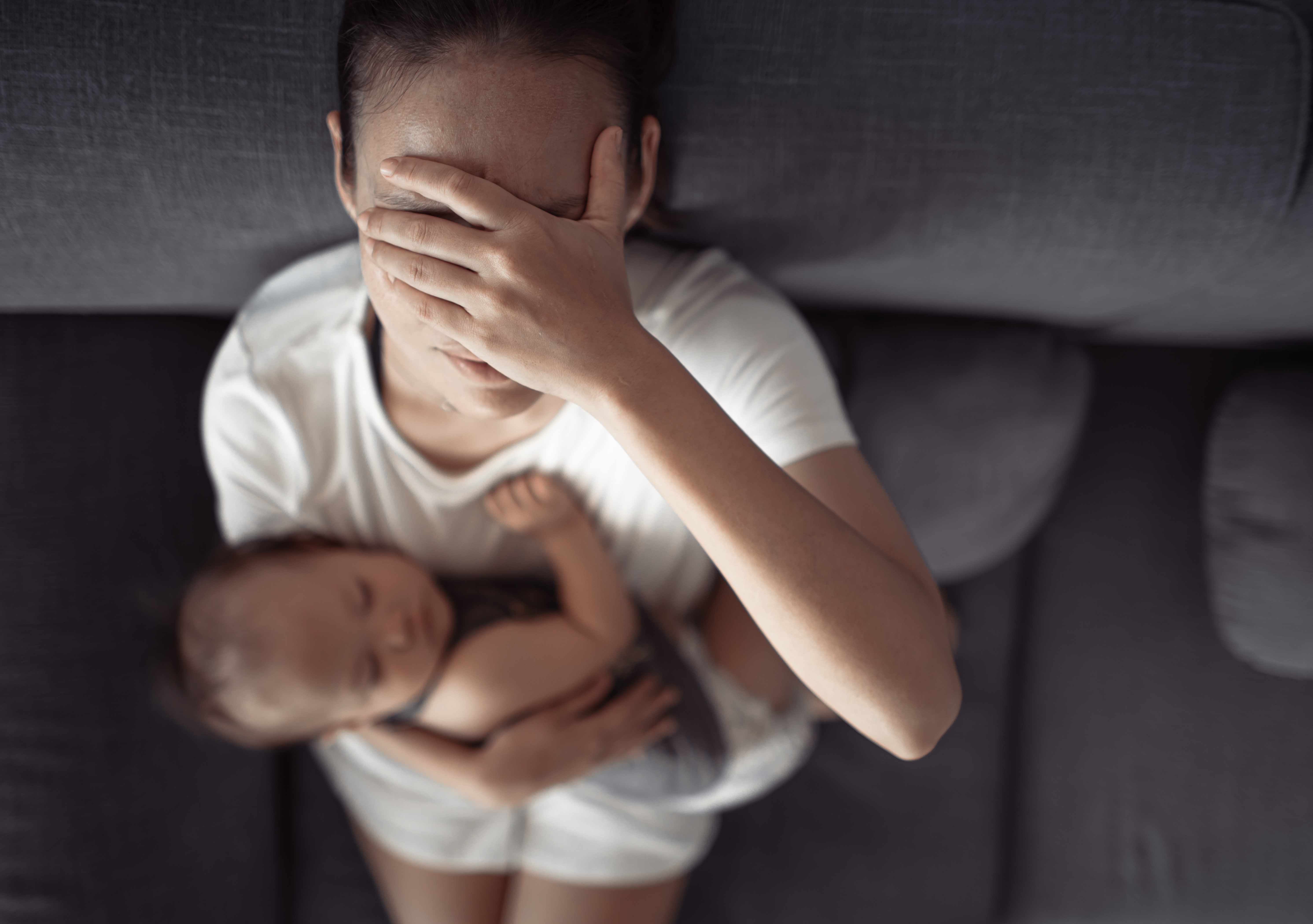 Una mujer sostiene a un bebé mientras se cubre la cara | Foto: Shutterstock