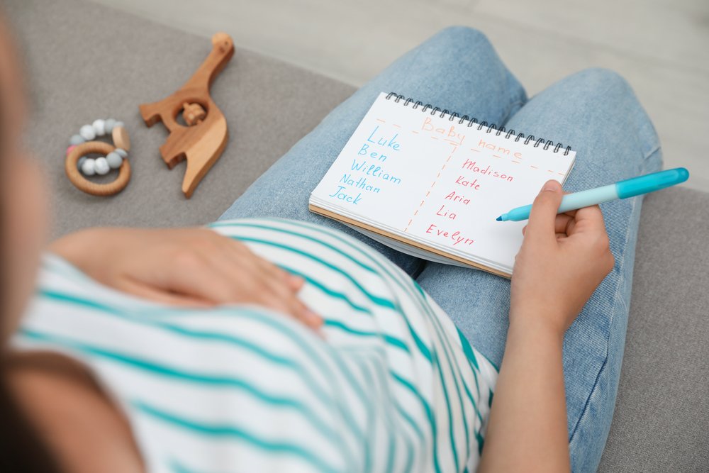 Mujer embarazada con un anotador y nombres de bebé. | Foto: Shutterstock