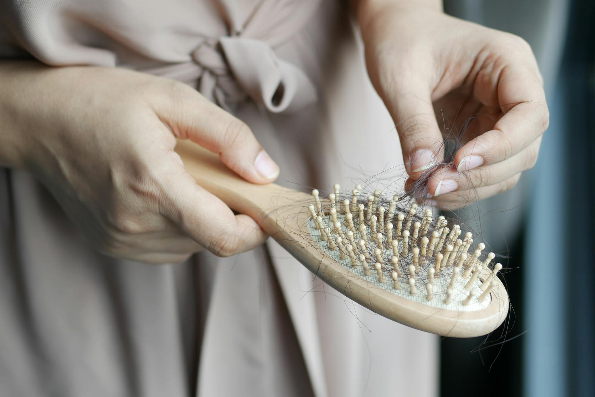 Foto recortada de una mujer quitando pelo de un cepillo | Fuente: Pexels