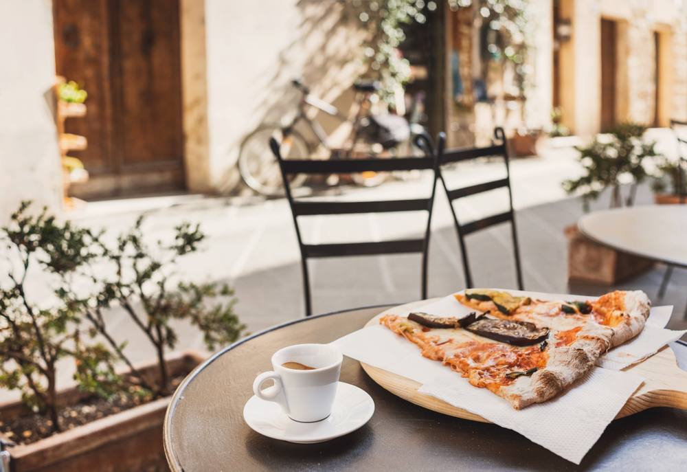 Taza de café expreso con trozos de pizza. | Fuente: Shutterstock