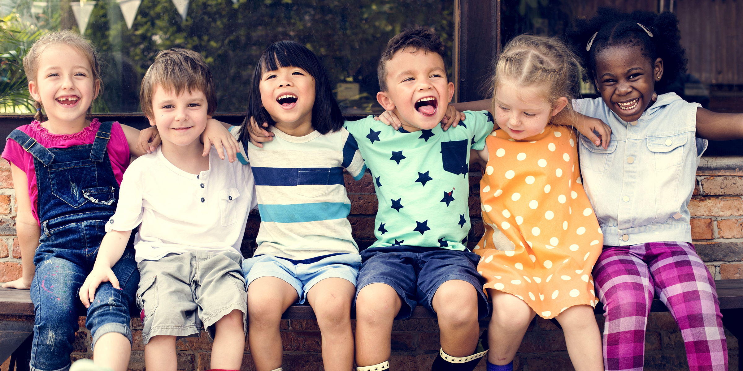 Niños sentados en un banco riendo | Fuente: Shutterstock