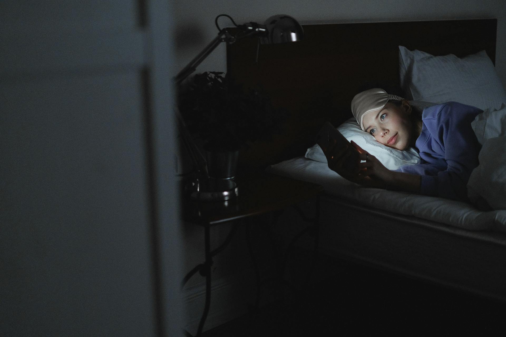 Una mujer en la cama sujetando un móvil | Fuente: Pexels