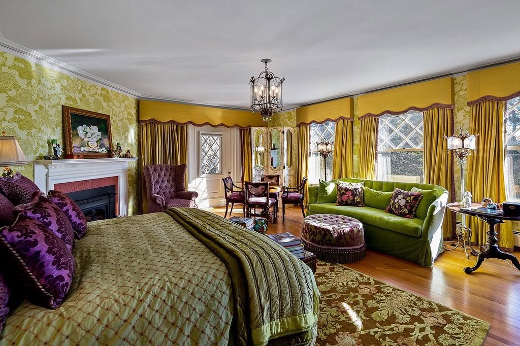 Una de las más de 20 habitaciones de la casa combina muebles en tonos verdes y morados, detalles florales, suelos de madera maciza y varias ventanas con cristales en forma de rombo. | Fuente: Facebook/LegacySIR