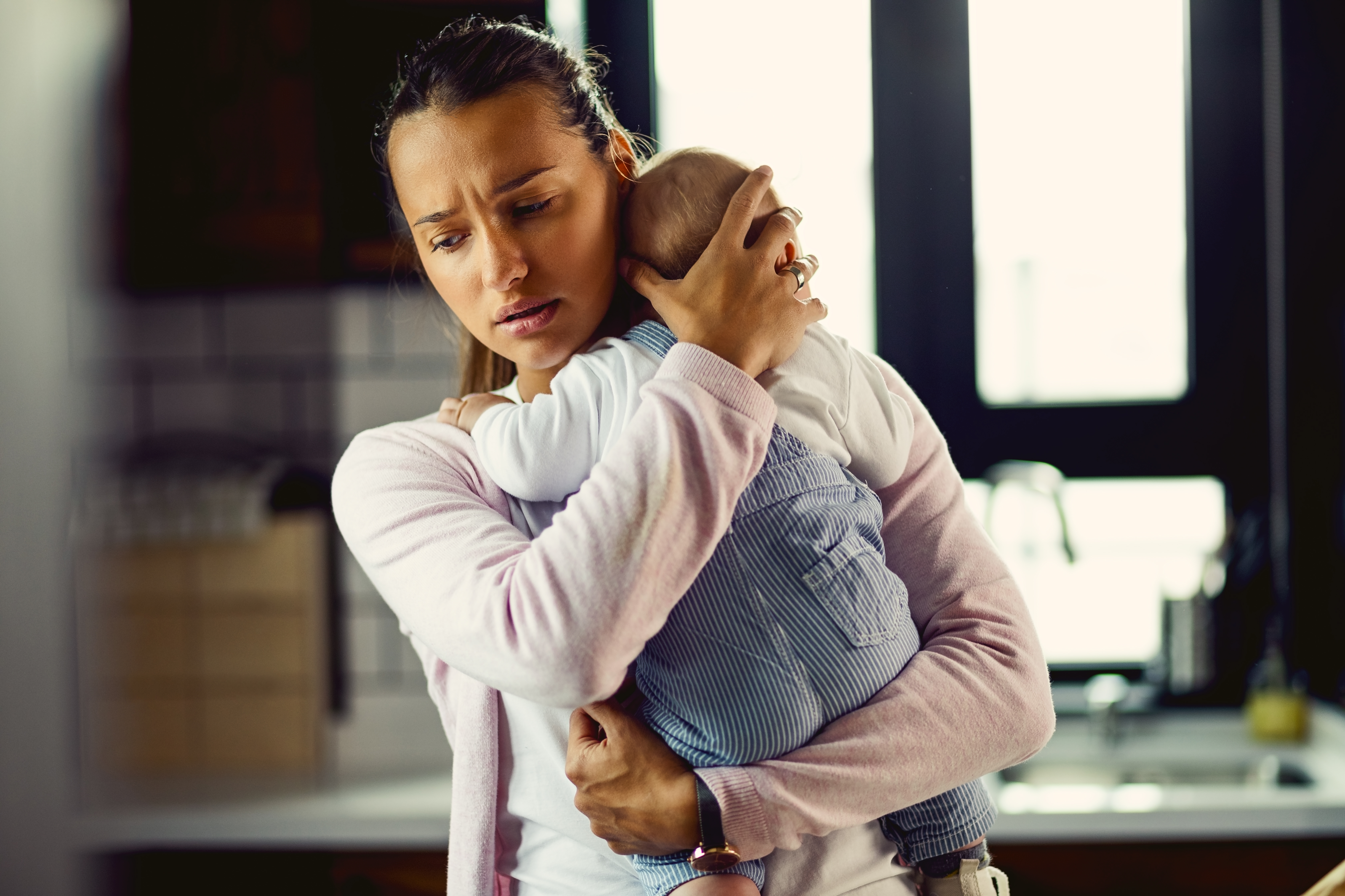 Una joven madre preocupada con su bebé en brazos | Foto: Getty Images