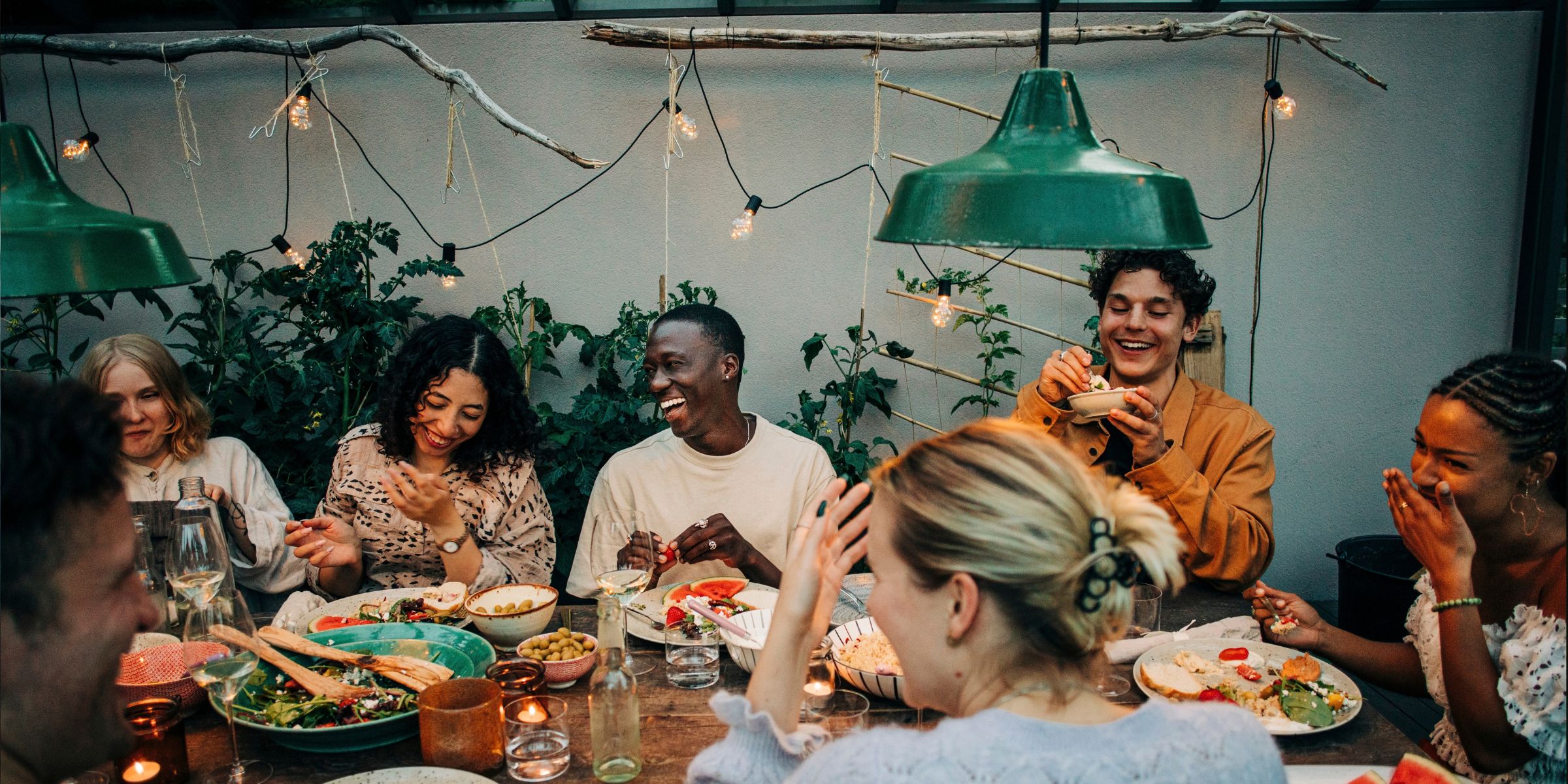 Unos compañeros de trabajo muy animados cenando juntos en un jardín | Fuente: Getty Images