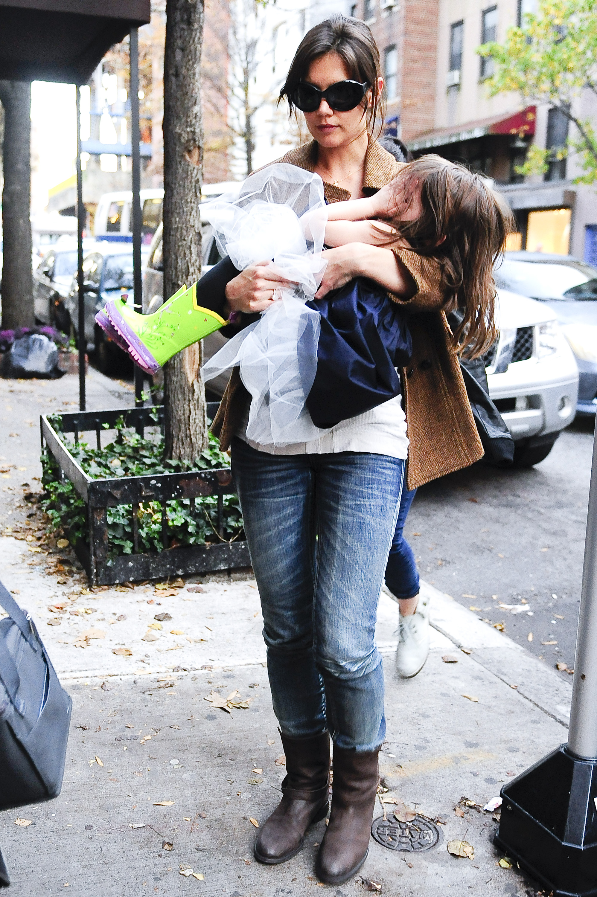 Katie Holmes lleva en brazos a Suri Cruise, que se tapa la cara, mientras pasean por Greenwich Village el 22 de noviembre de 2009 | Fuente: Getty Images