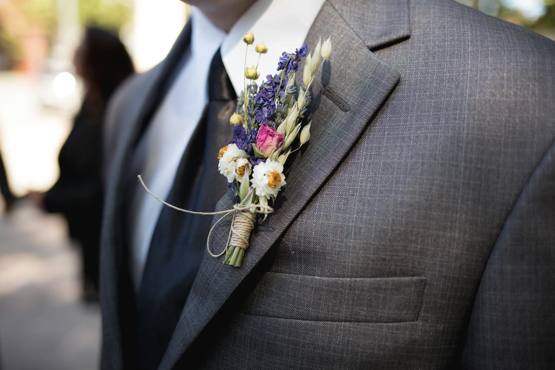 Un boutonnière de flores en la chaqueta del traje gris del novio | Fuente: Pexels