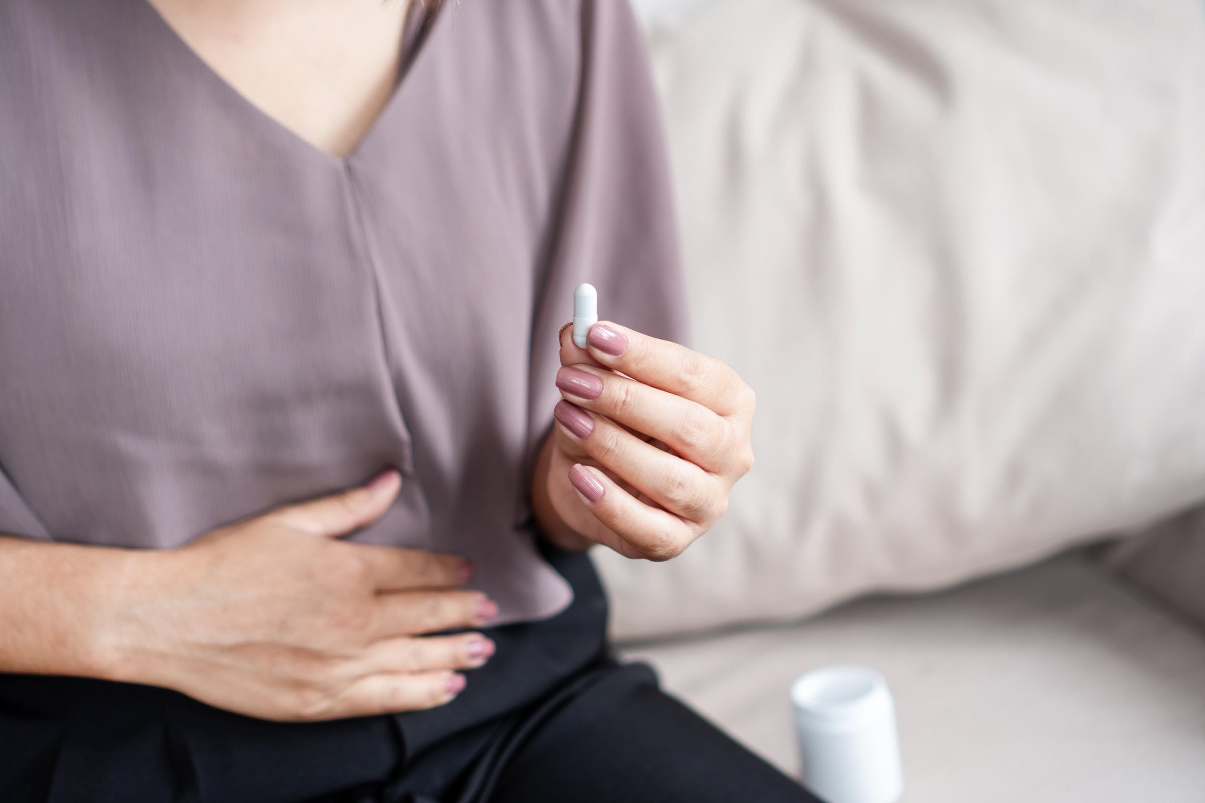 Una mujer toma una píldora para aliviar su dolencia digestiva | Fuente: Getty Images