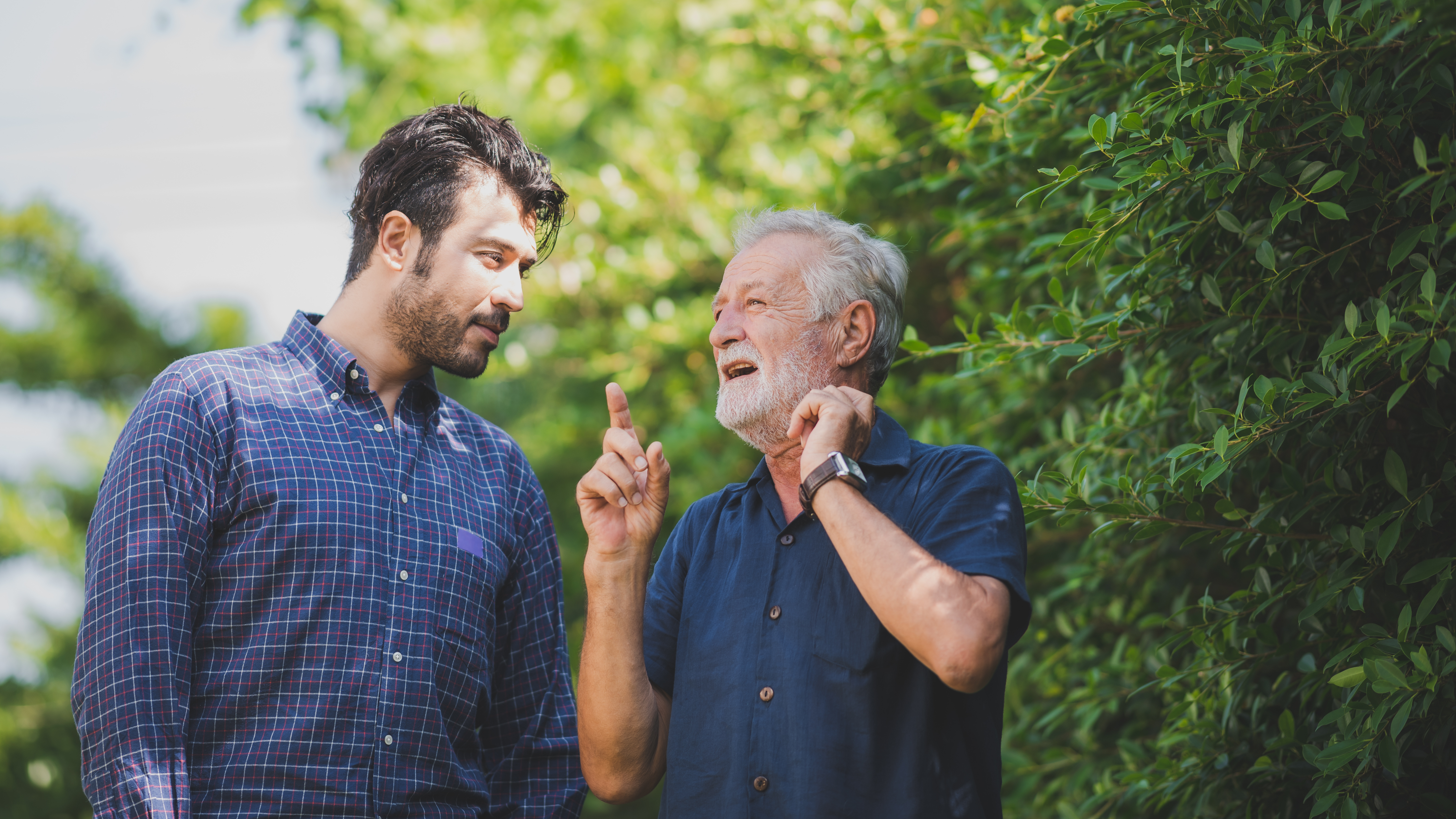 Un hombre mayor estrechando lazos con otro más joven en el exterior | Foto: Shutterstock