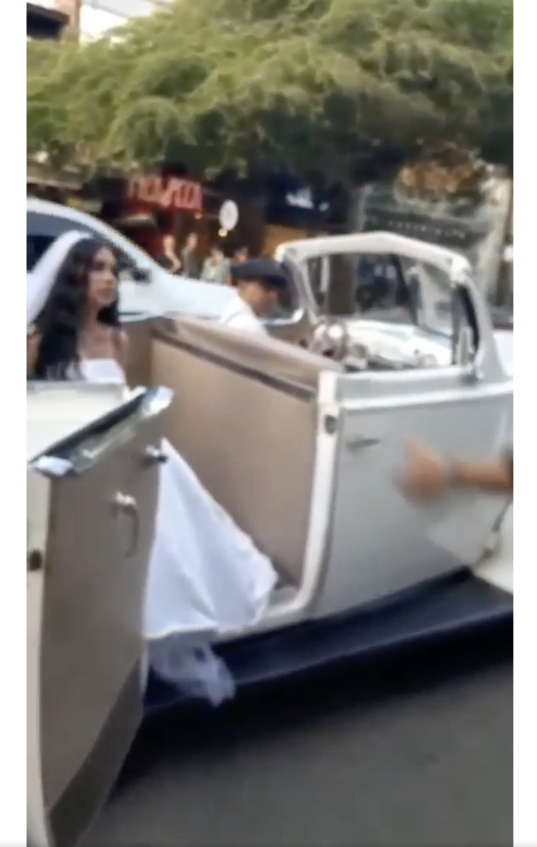 Una mujer vestida con un traje de novia blanco aparece en un clásico vehículo nupcial en la carretera. | Foto: facebook.com/maspopulareventos