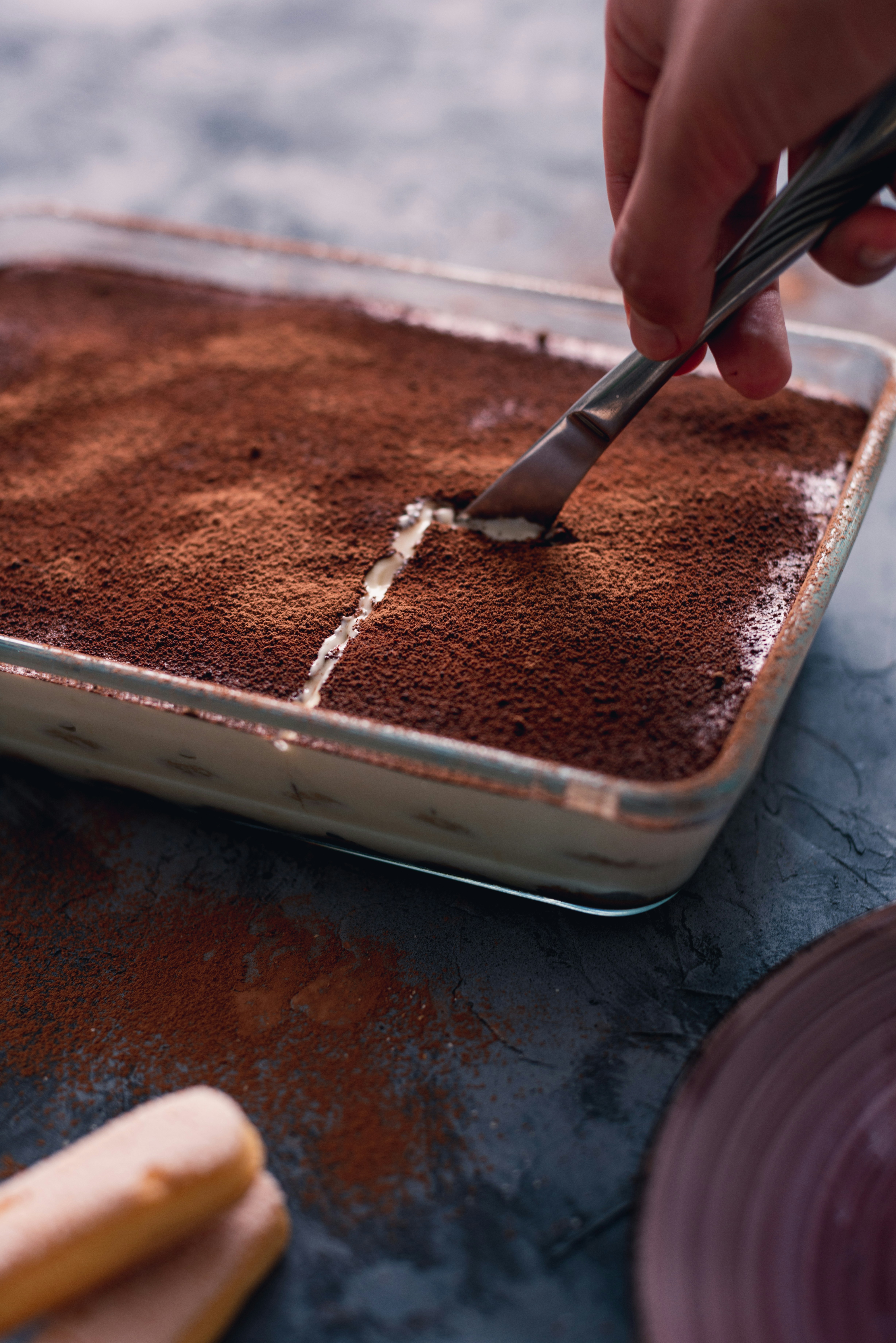 Una persona che taglia una fetta di tiramisù | Fonte: Unsplash