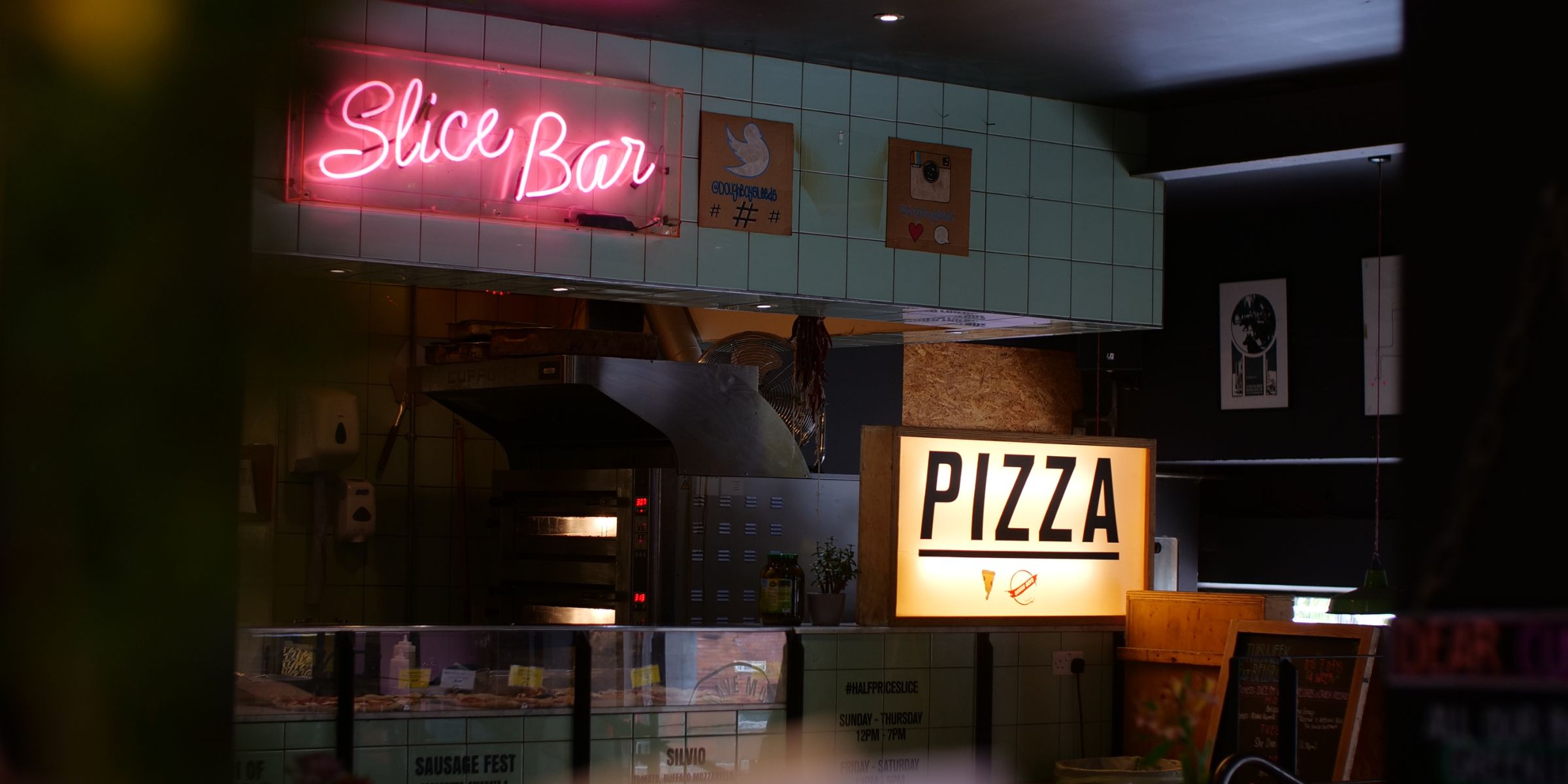 Interior de una pizzería local con un letrero de neón y servicio de mostrador | Fuente: Shutterstock