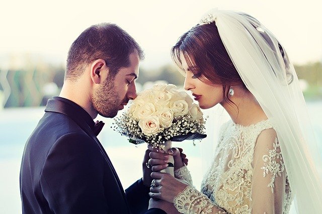 Recién casados enamorados sosteniendo el ramo de flores. Fuente: Pixabay.