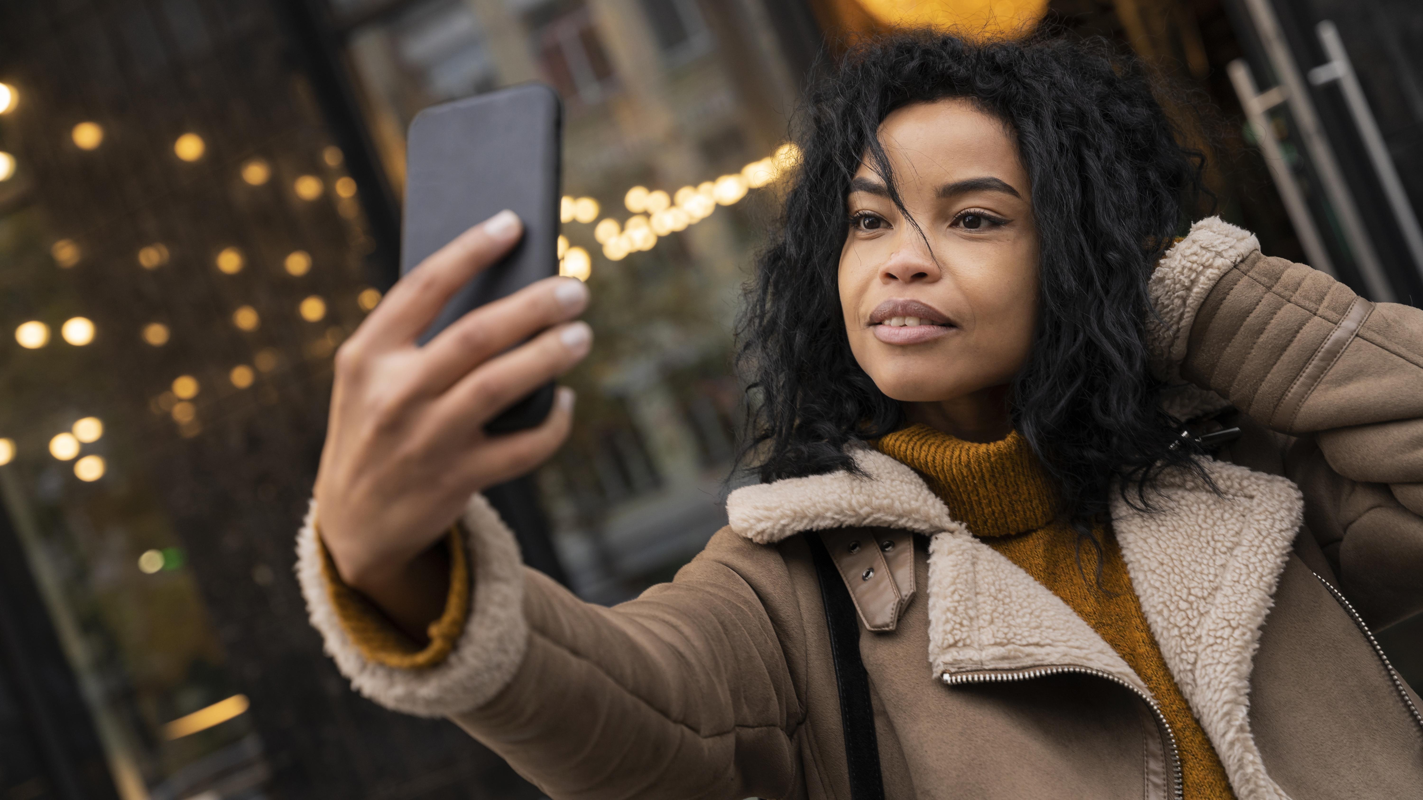 Una mujer tomándose un selfie con su teléfono | Fuente: Freepik