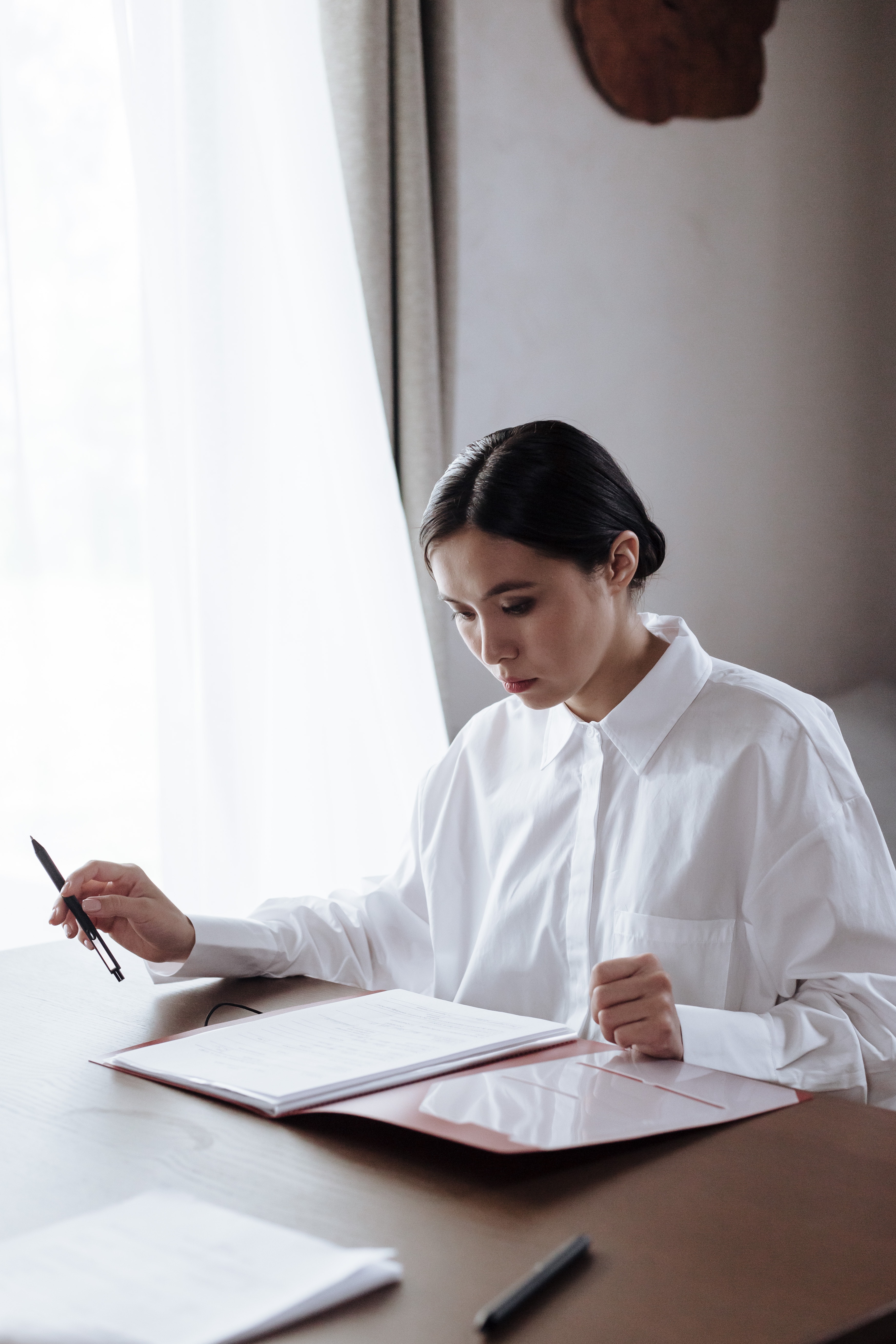Una mujer sentada detrás de un escritorio y revisando un documento. | Foto: Pexels