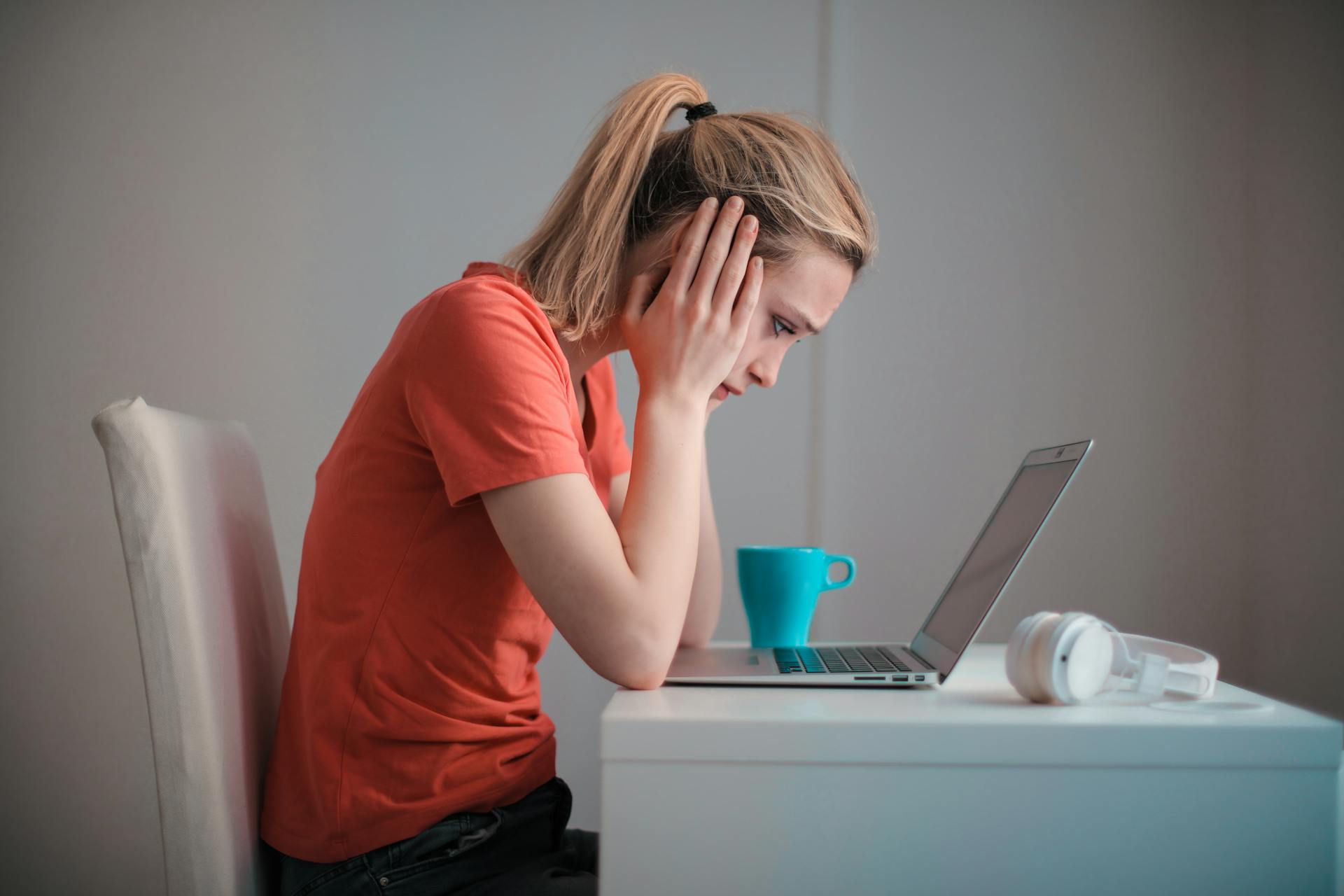 Una mujer mirando su portátil y sujetándose la cabeza | Fuente: Pexels
