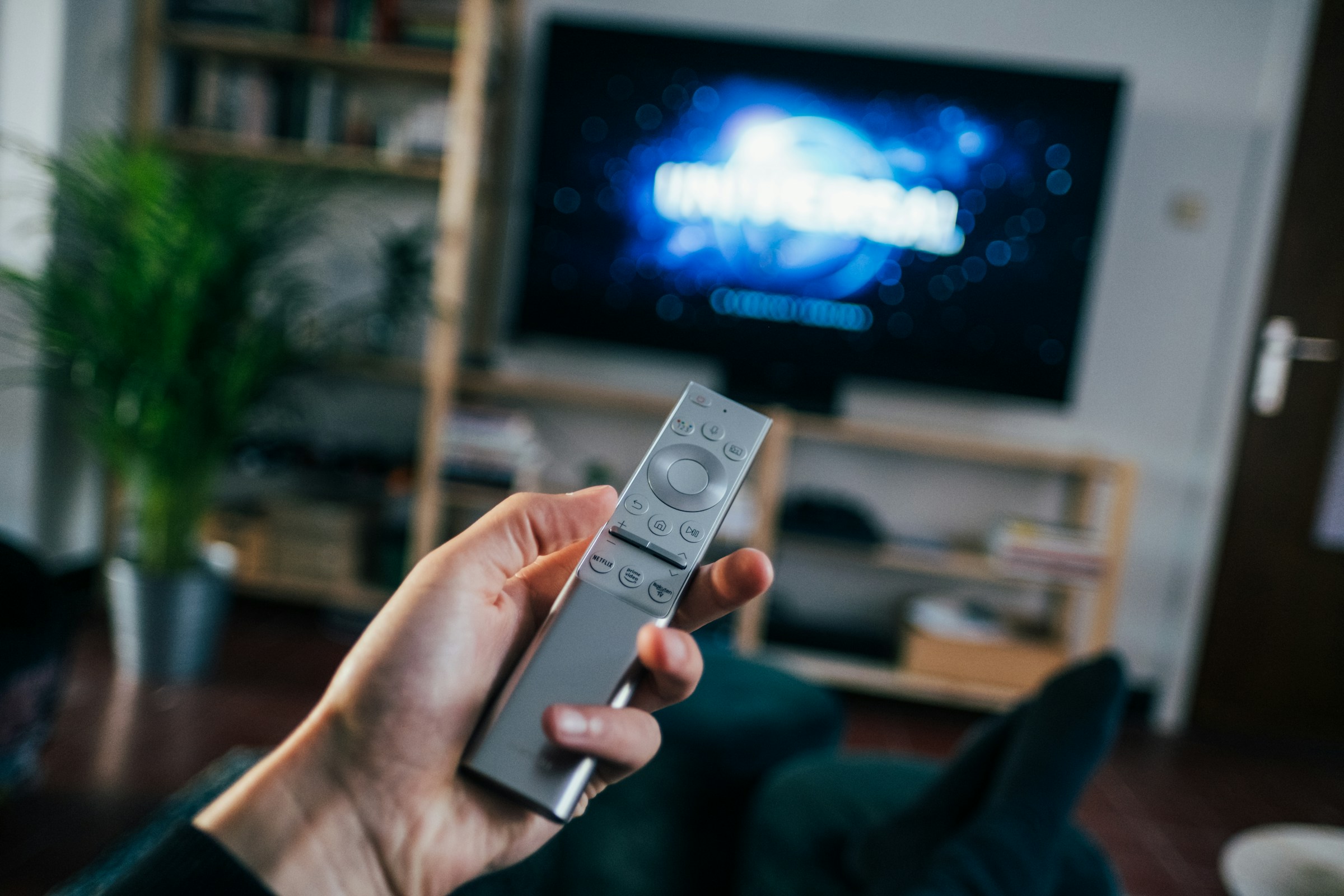 La mano de un hombre sujetando un mando a distancia en un salón | Fuente: Unsplash