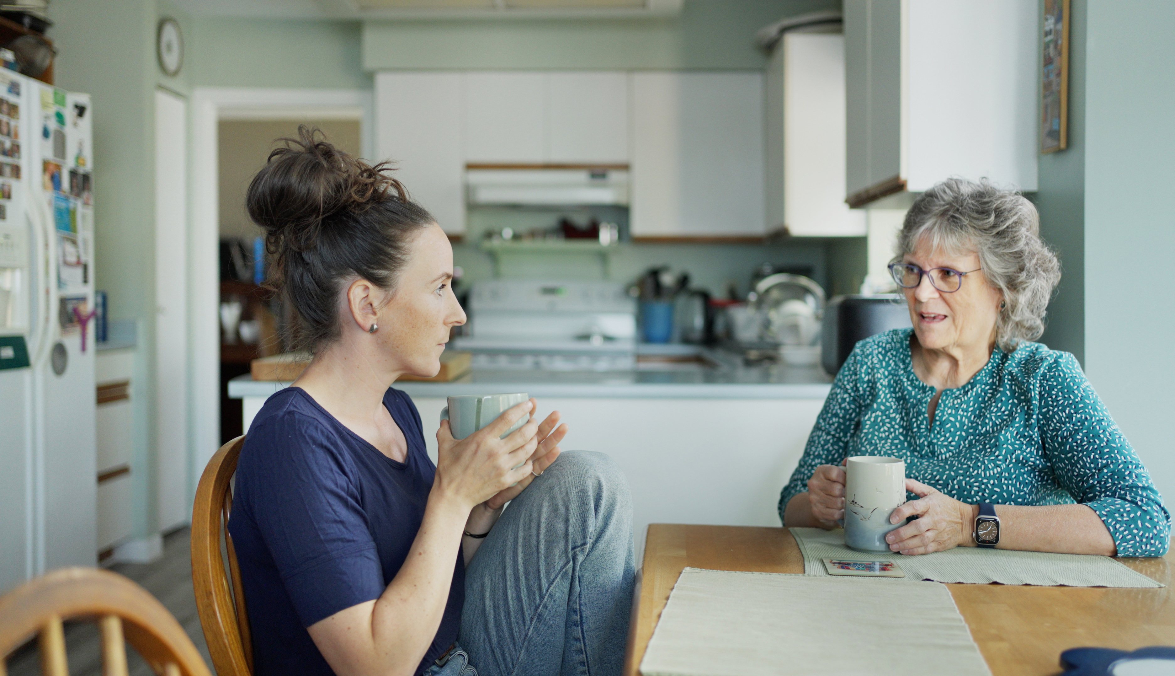 Joven charlando con su madre tomando el té durante una visita | Foto: Getty Images