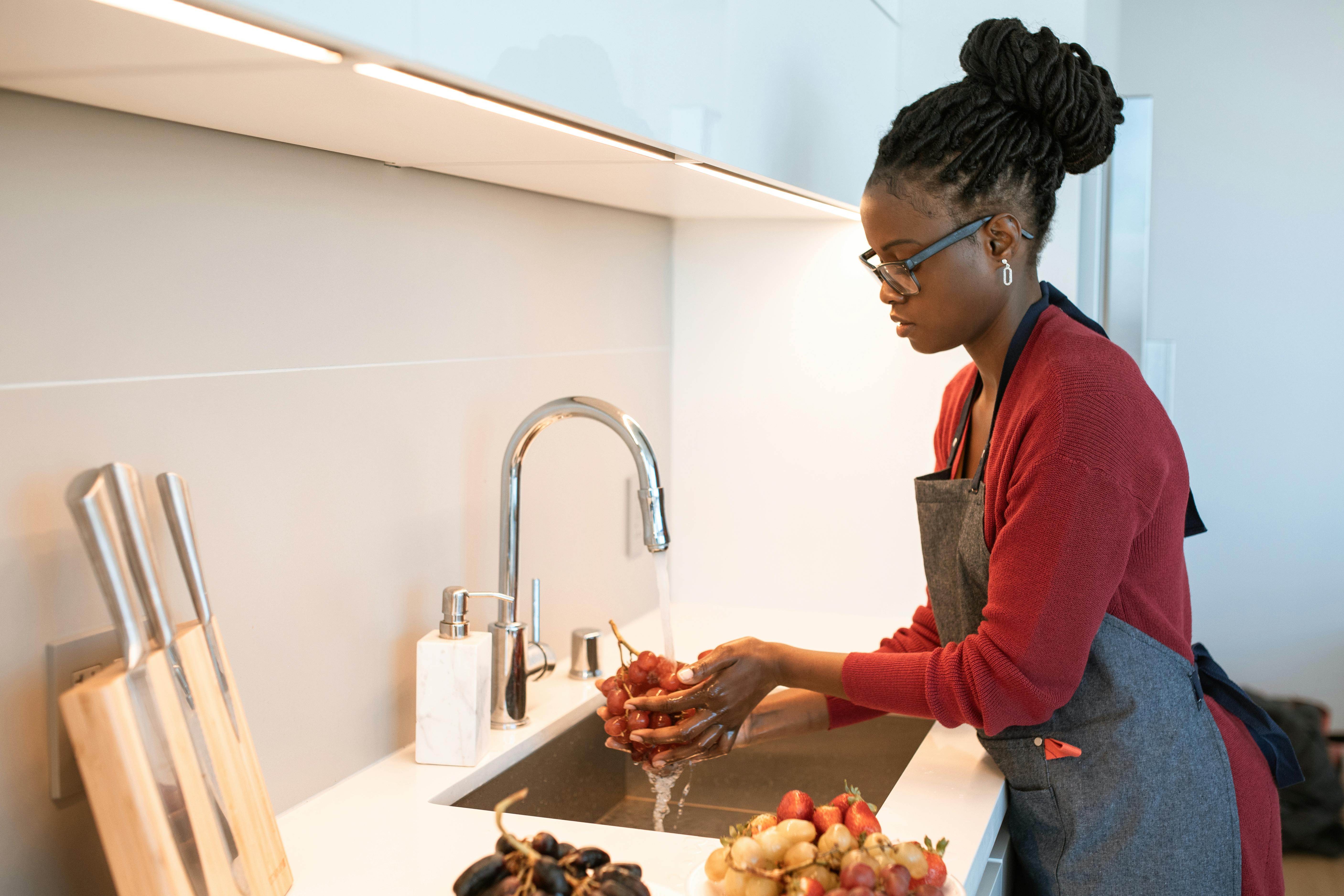 Una mujer lavando fruta en casa | Fuente: Pexels