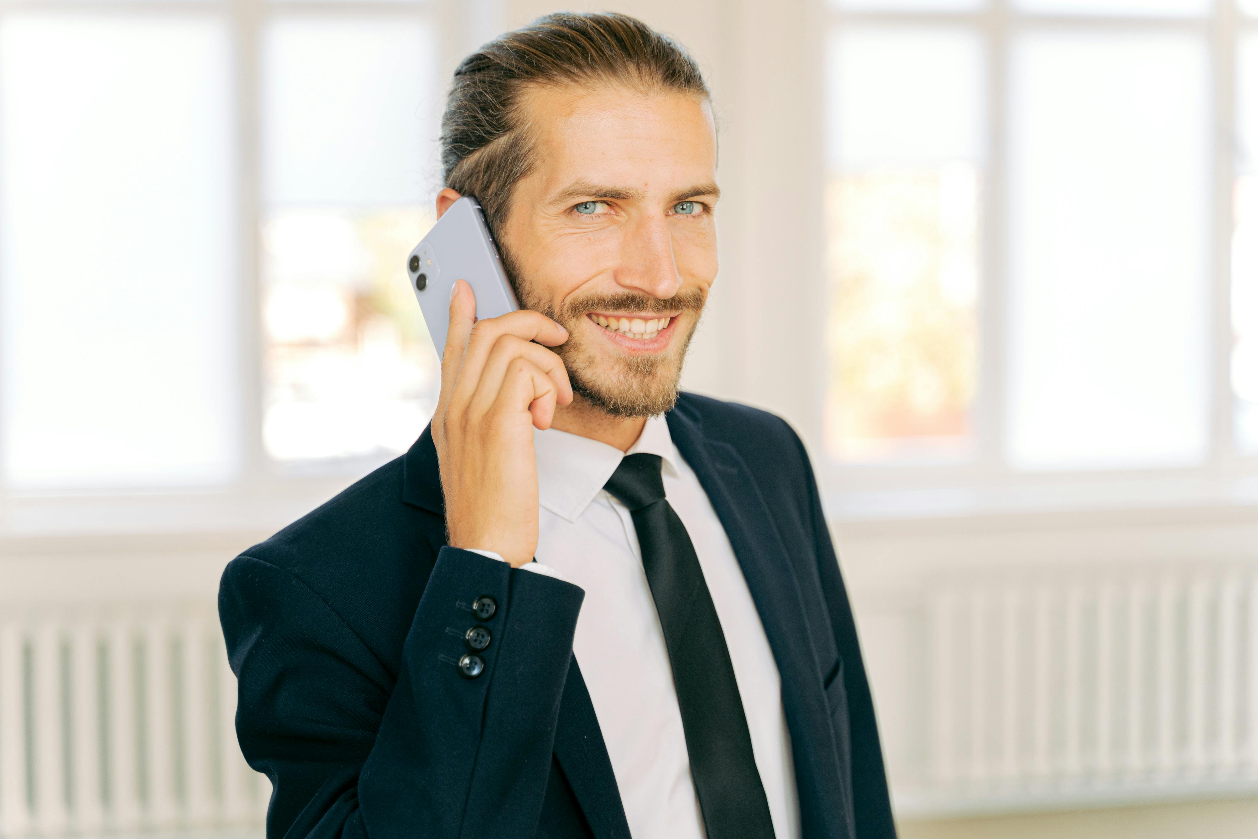 Un hombre sonriente en una llamada telefónica | Fuente: Pexels