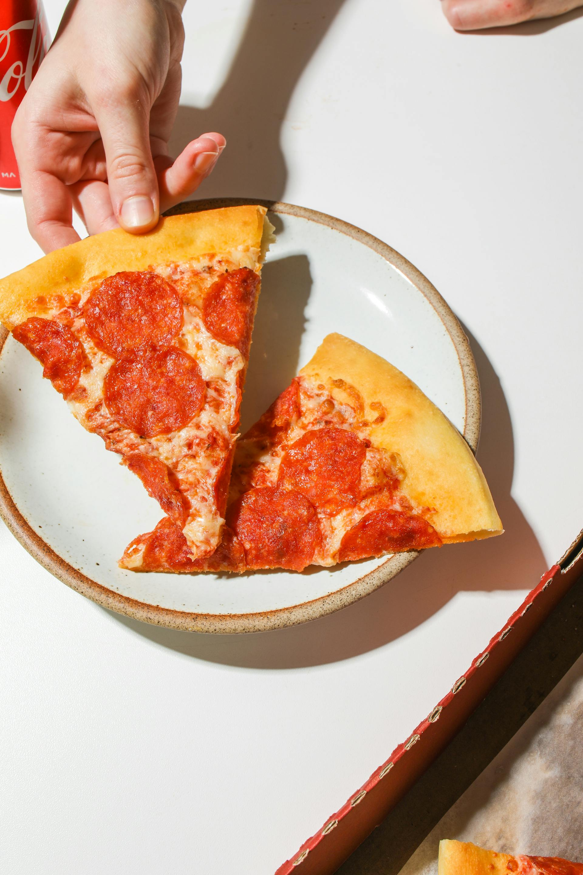 Alguien cogiendo una porción de pizza de un plato | Fuente: Pexels