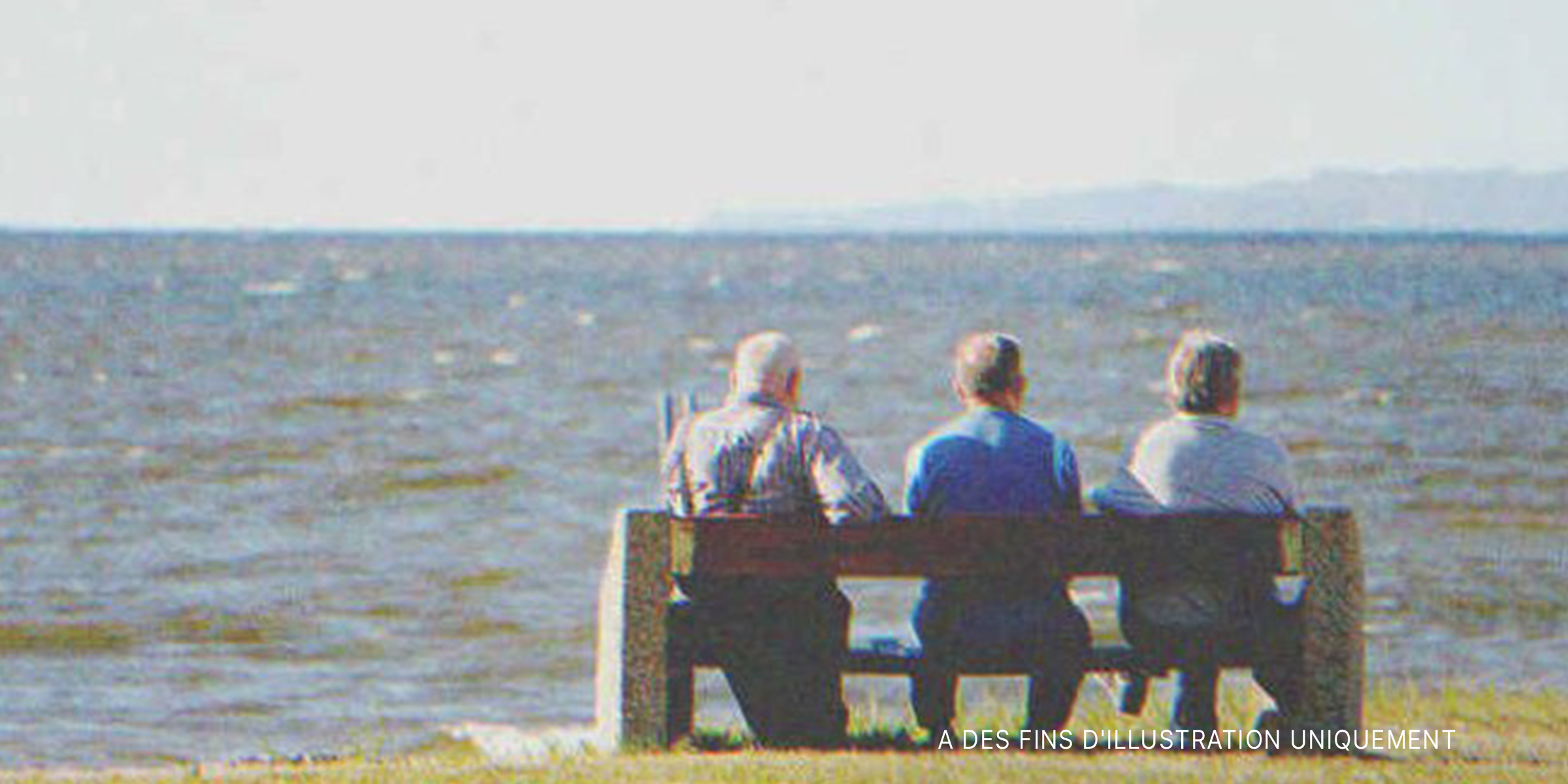 Trois hommes âgés assis sur un banc au bord de la mer | Source : Shutterstock