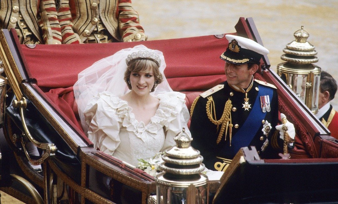 Charles y Diana, quien lucía un vestido de novia diseñado por David y Elizabeth Emanuel y la Tiara de la familia Spencer, viajan en un carruaje abierto, desde la Catedral de St. Paul hasta el Palacio de Buckingham, luego de su boda el 29 de julio de 1981 en Londres, Inglaterra. | Foto: Getty Images