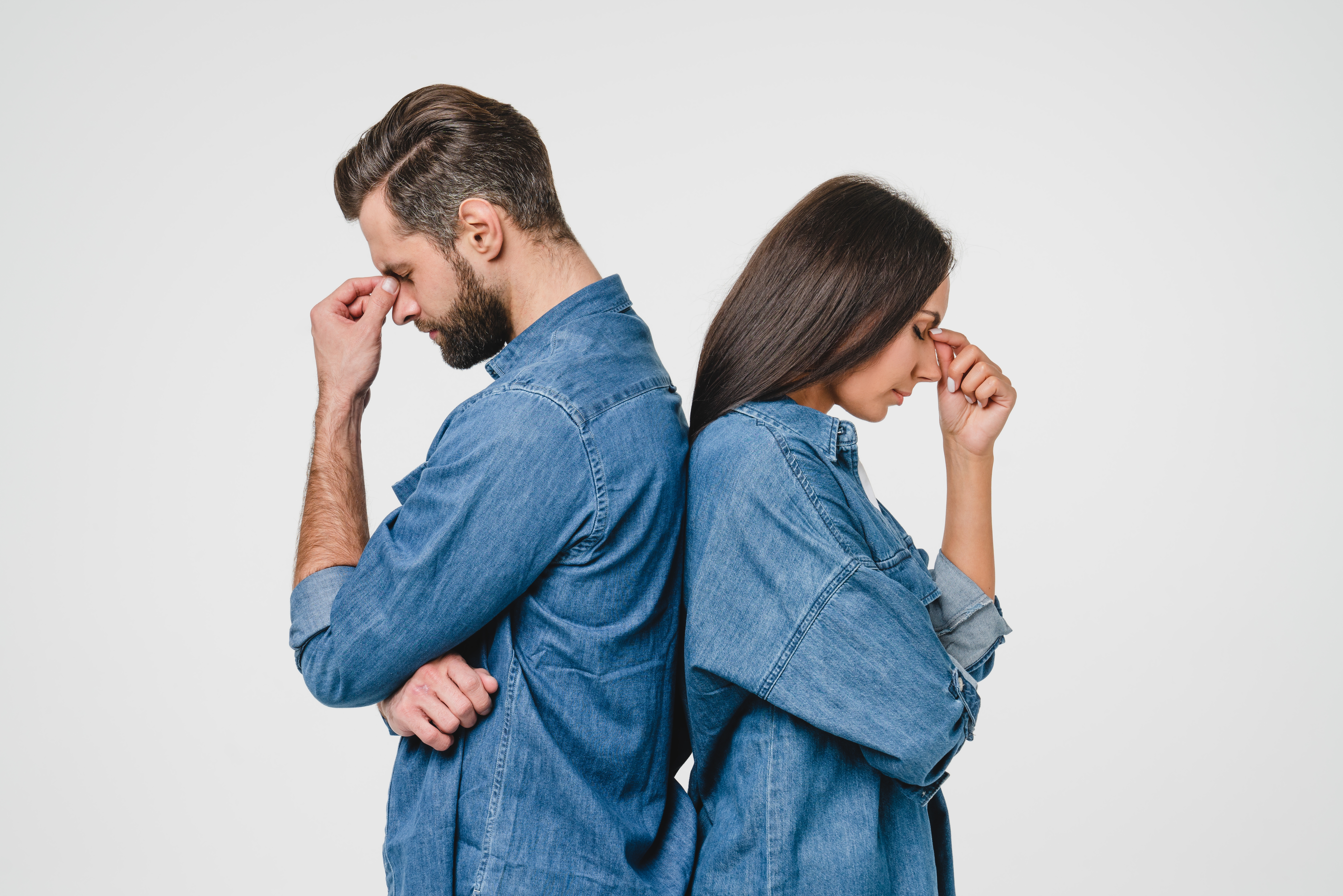 Pareja disgustada de espaldas pellizcándose los puentes de la nariz | Foto: Shutterstock