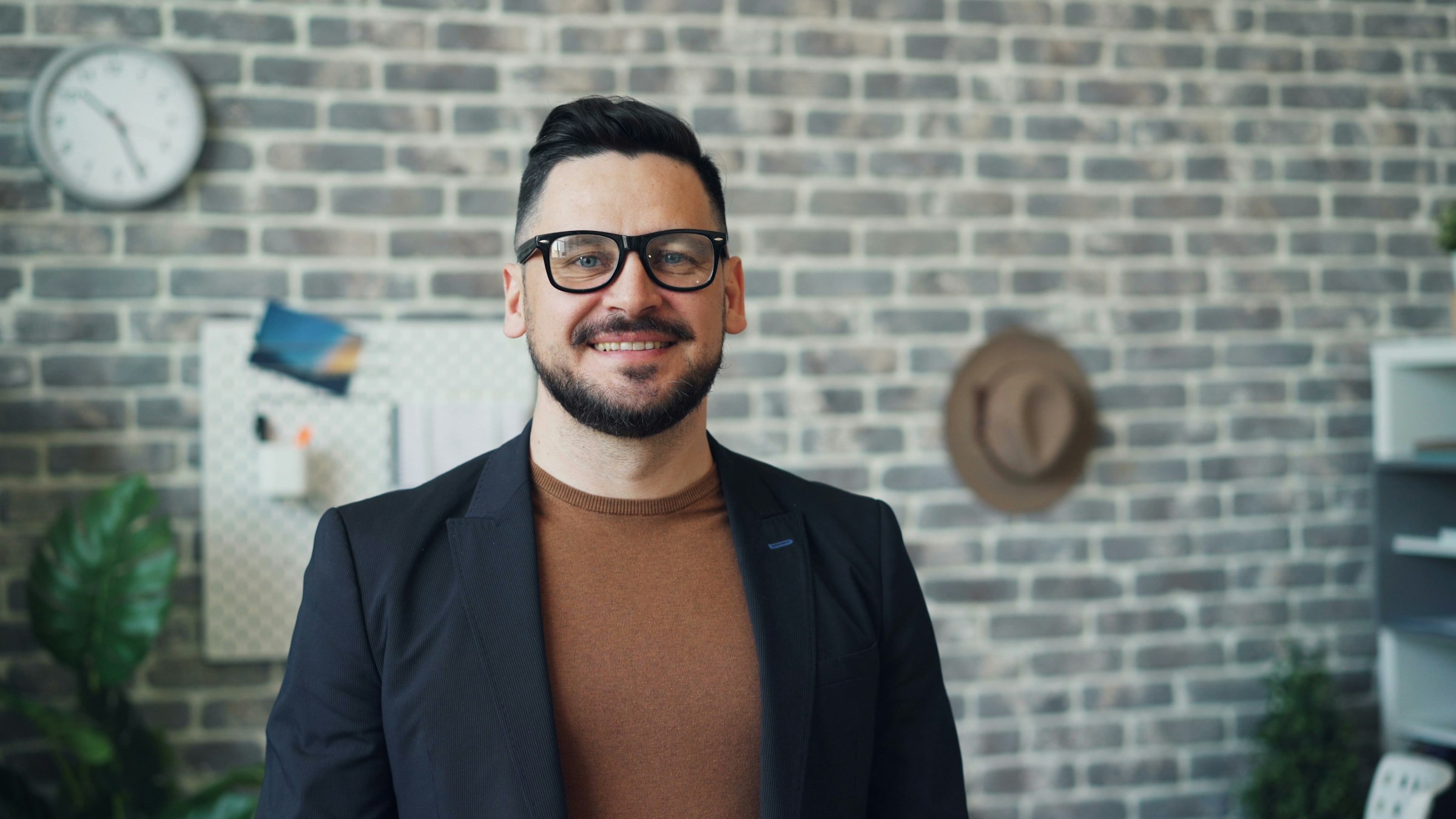 Un hombre sonriente frente a un muro de ladrillo | Fuente: Unsplash