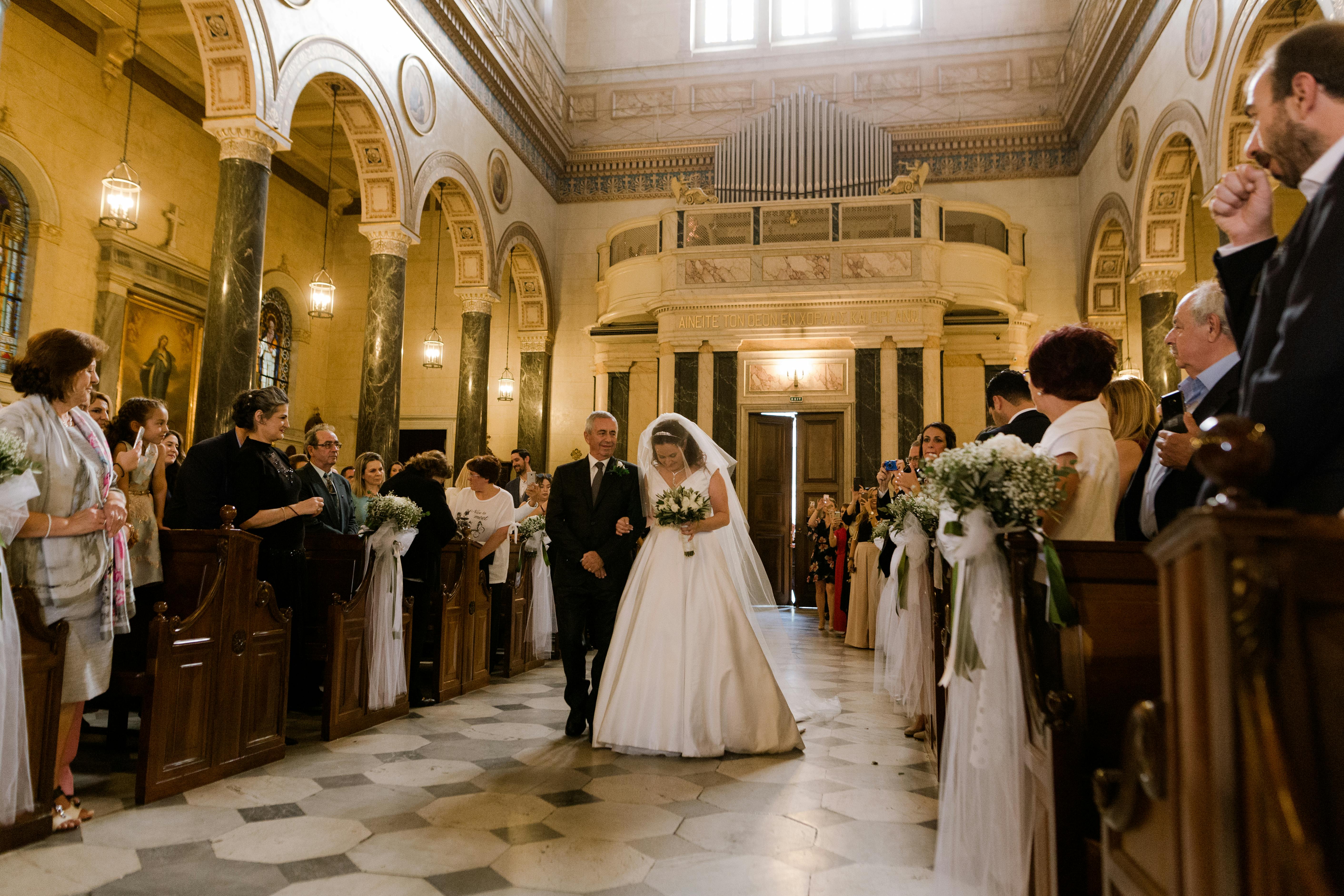 Un hombre acompaña a una novia por el pasillo de una iglesia | Fuente: Pexels