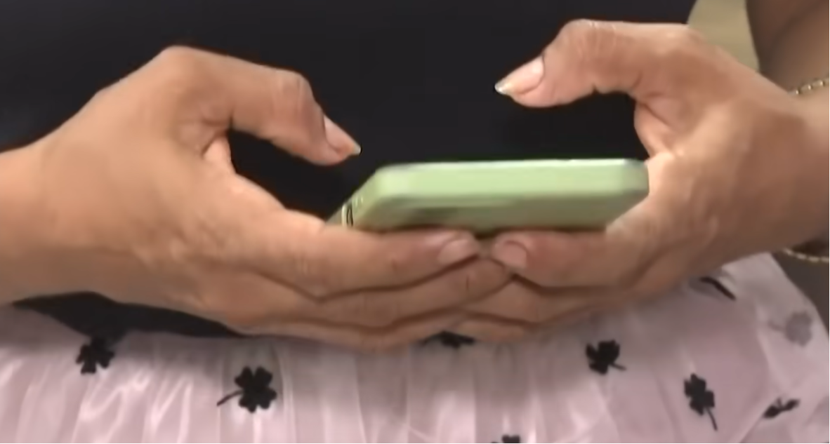 Una mujer revisando un teléfono móvil | Fuente: YouTube/Noticias RCN