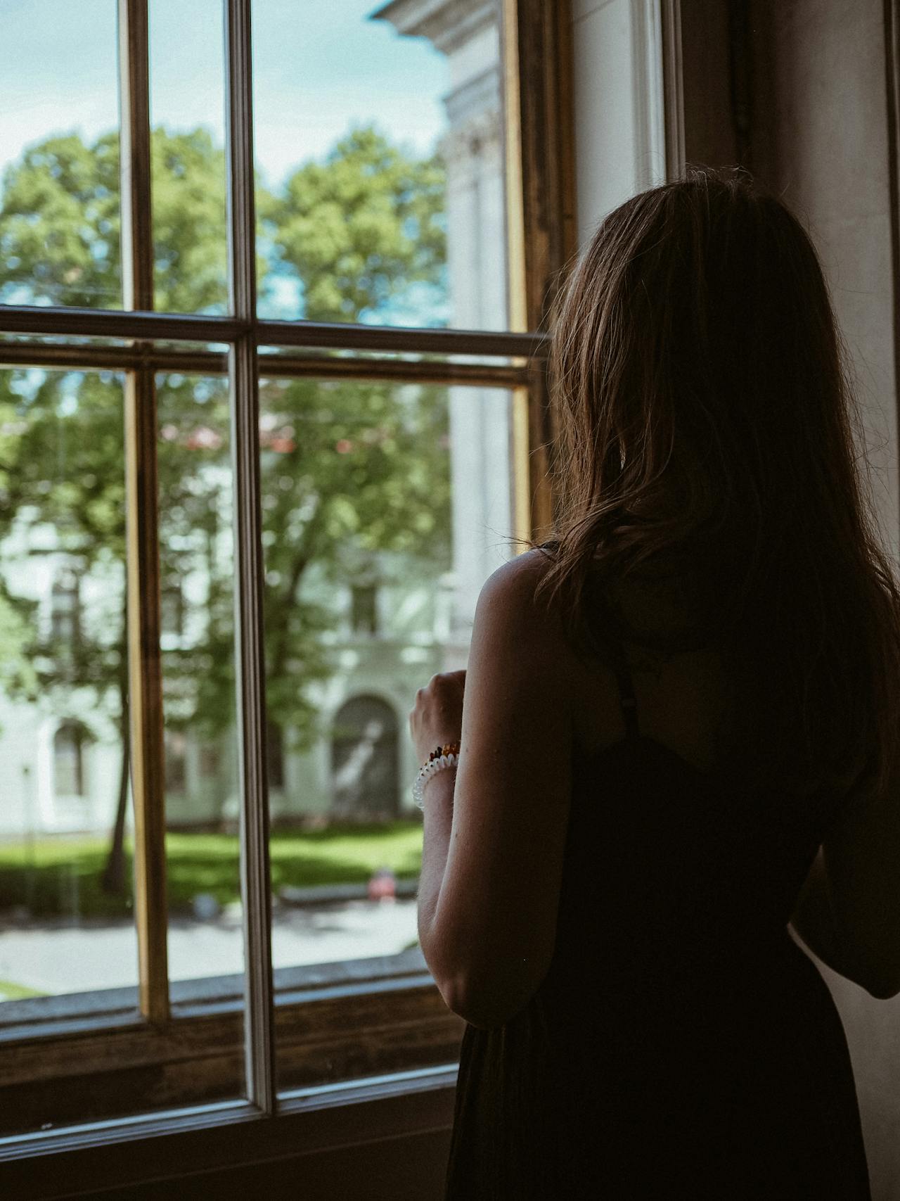 Una mujer de pie junto a la ventana | Fuente: Pexels