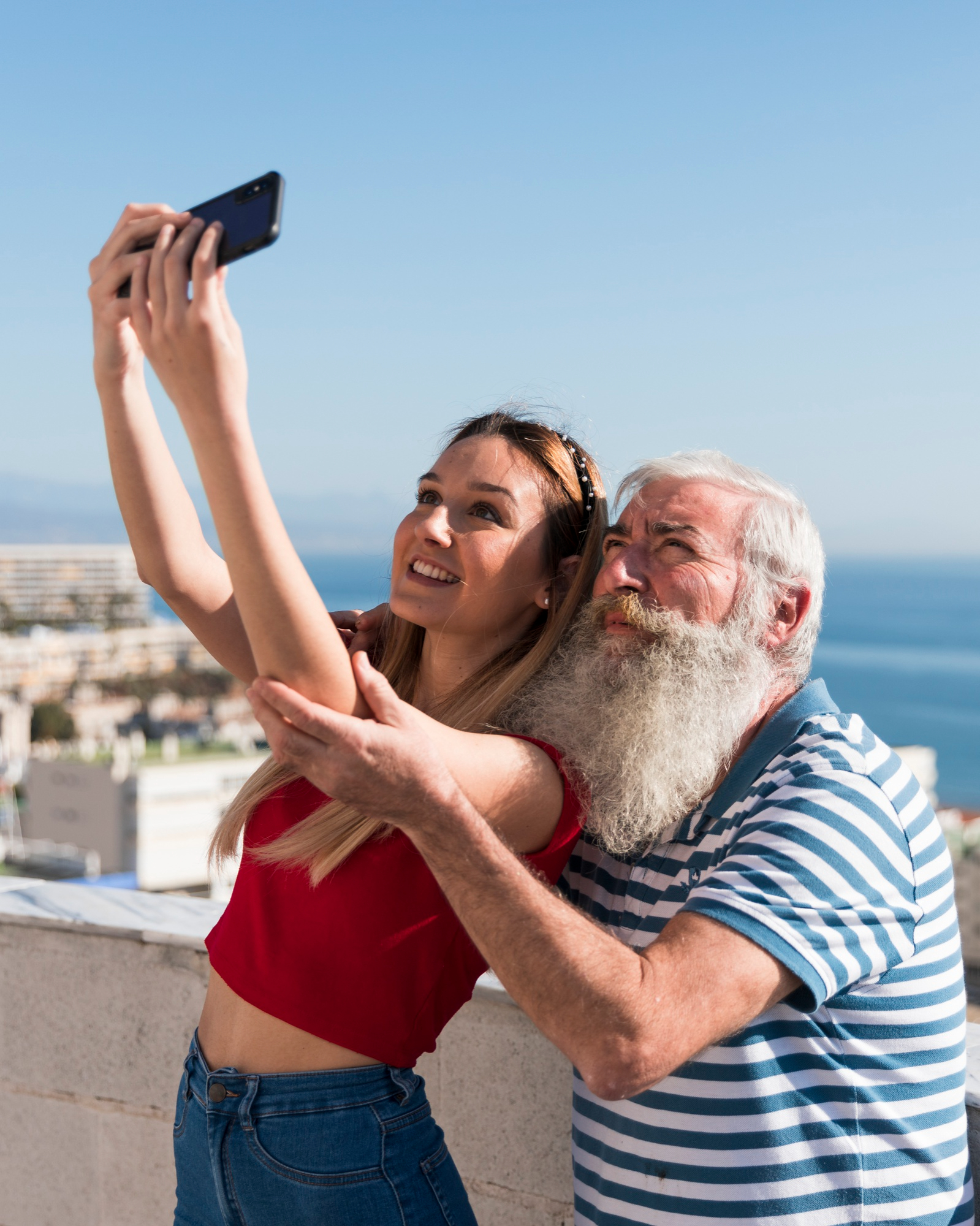Un hombre mayor tomándose un selfie con una chica joven | Foto: Freepik